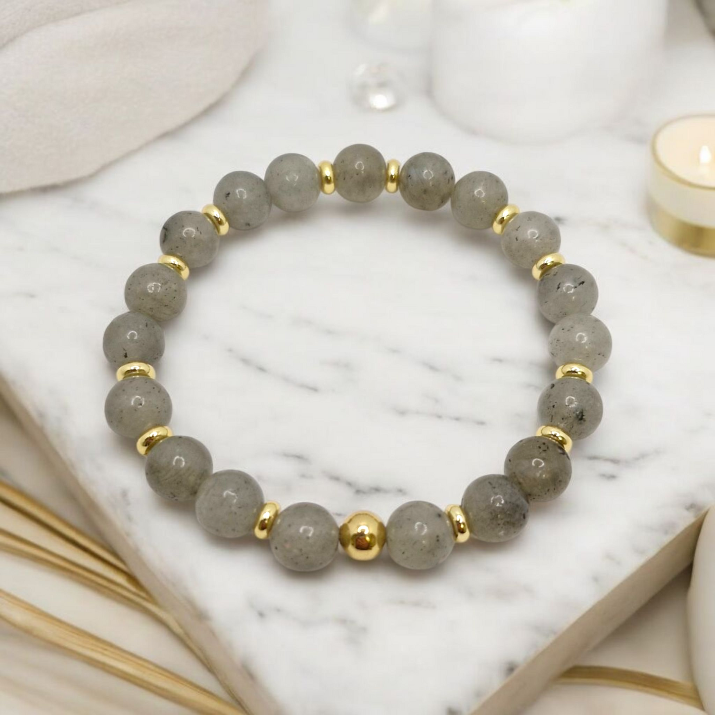 Gray beaded bracelet with gold accents on a marble surface