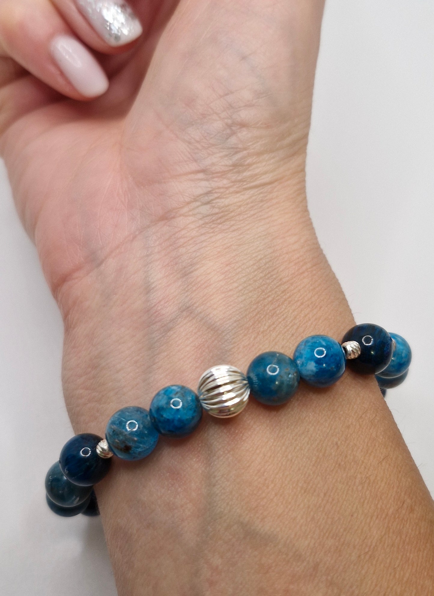 Bracelet with blue and black beads on a wrist against a white background