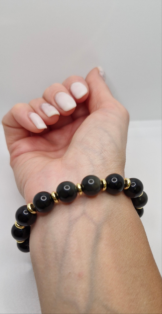Close-up of natural Black Rainbow Obsidian beads with gold-plated brass disks on stretch bracelet