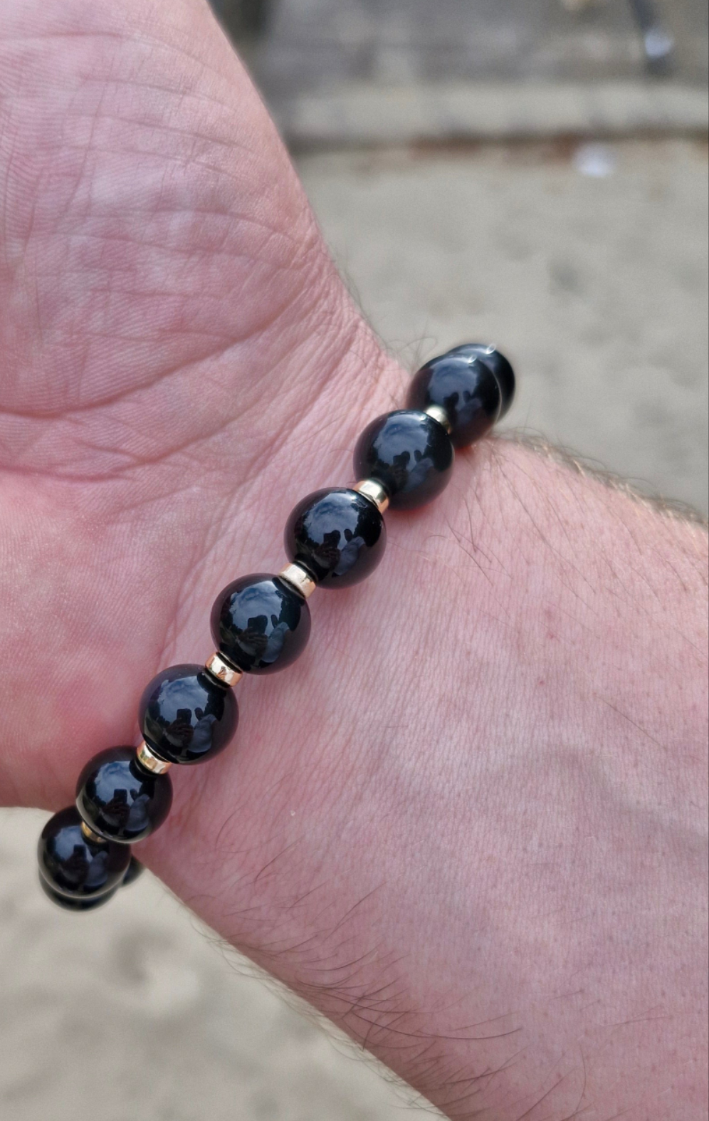 Unisex Black Obsidian stretch bracelet with 4mm Gold Filled rondelle bead displayed on wrist.