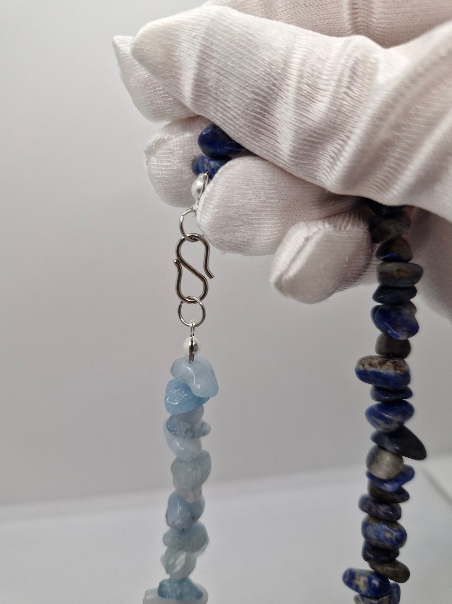 Close-up of stainless steel S-hook clasp on aquamarine and lapis lazuli chip necklace, durable and easy to fasten.