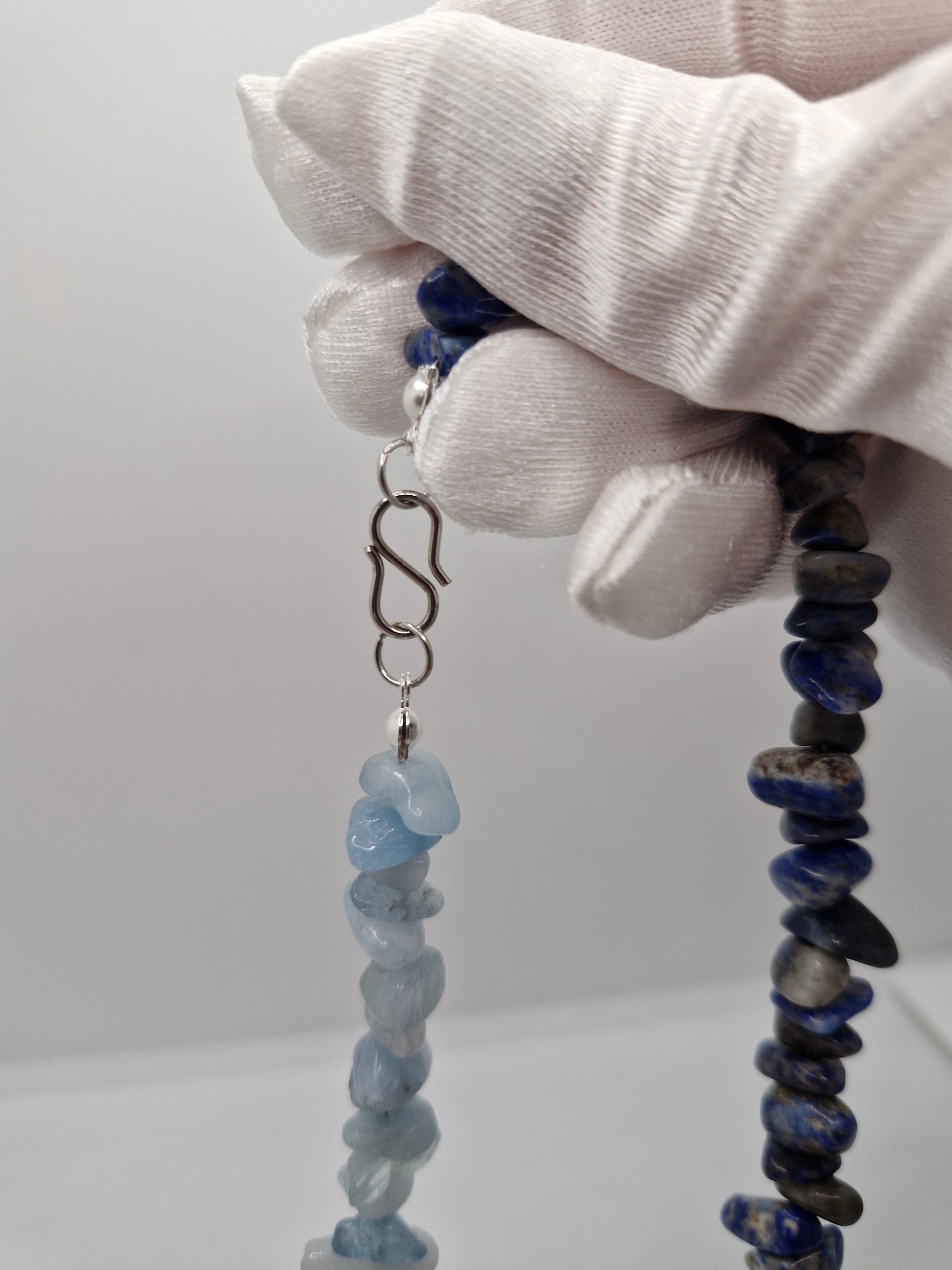 Close-up of stainless steel S-hook clasp on aquamarine and lapis lazuli chip necklace, durable and easy to fasten.