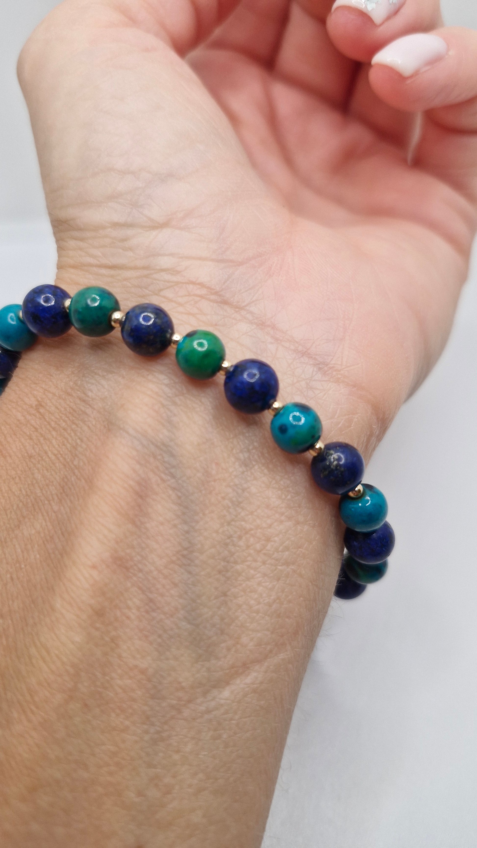 Hand wearing a handmade Lapis Lazuli and Chrysocolla stretch bracelet with gold filled beads, showcasing its elegant fit and vibrant colors