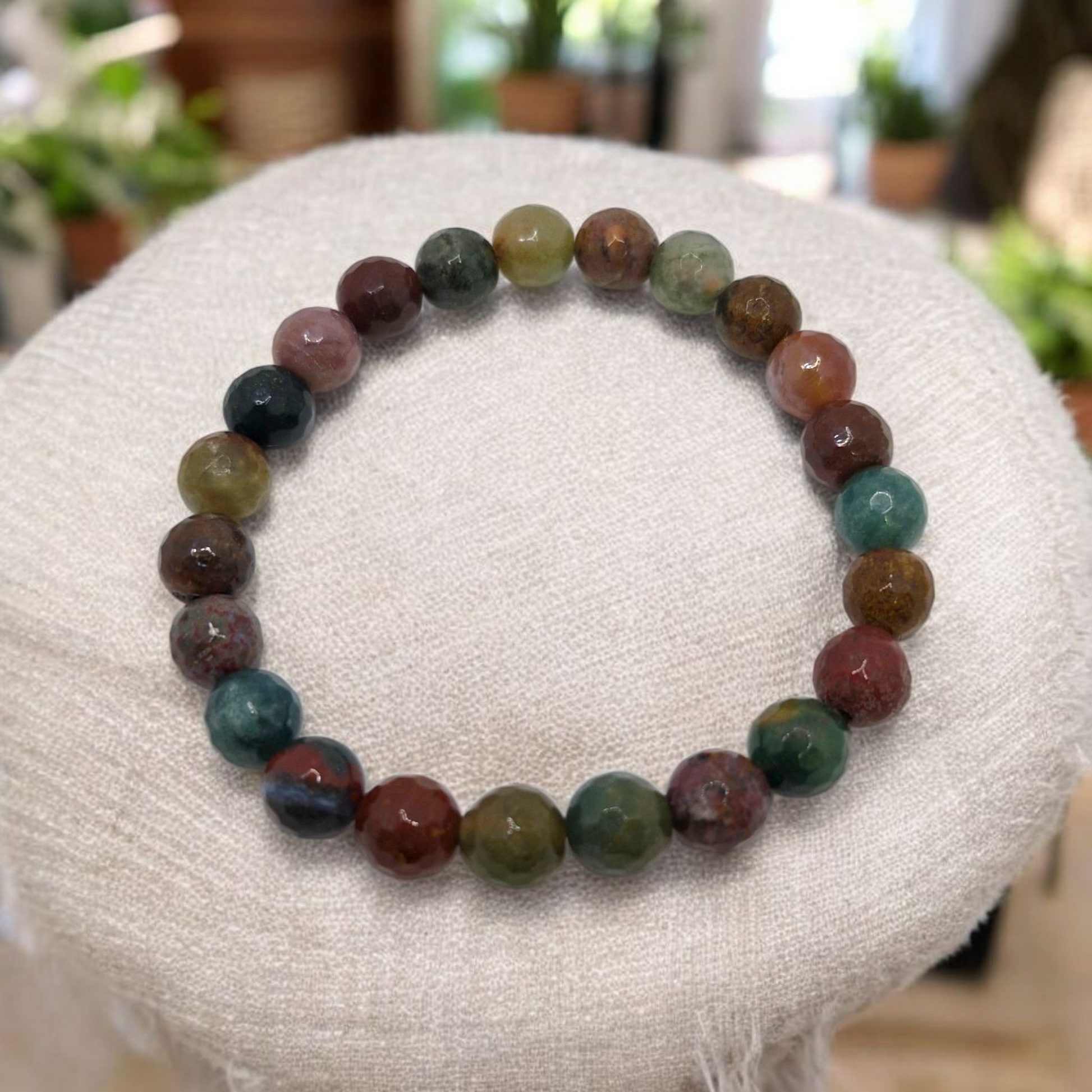 Close-up of Grade AA Indian Agate bracelet, faceted round beads on stretch cord with earthy green and brown hues.