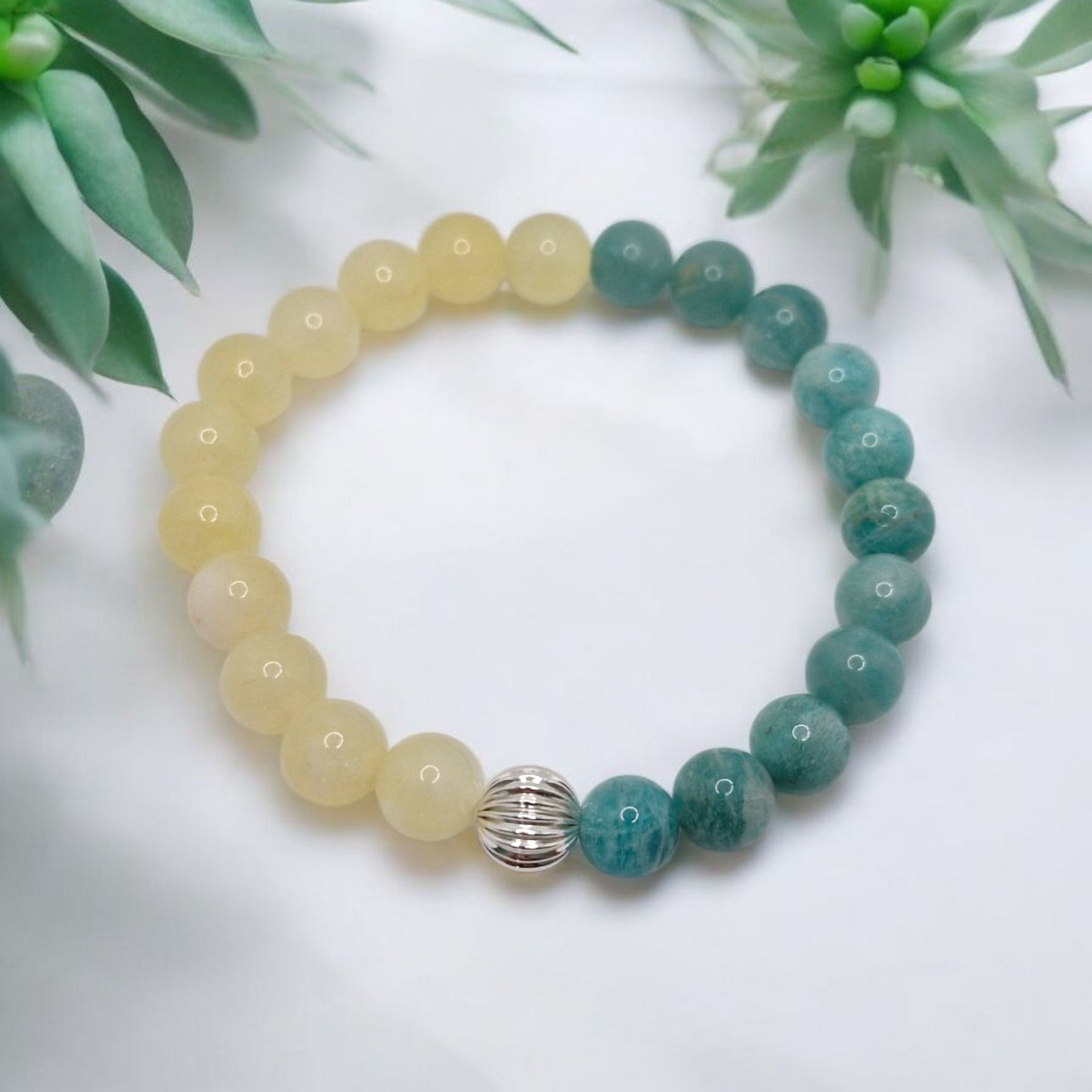 Beaded bracelet with yellow and green beads on a white background with green plants.