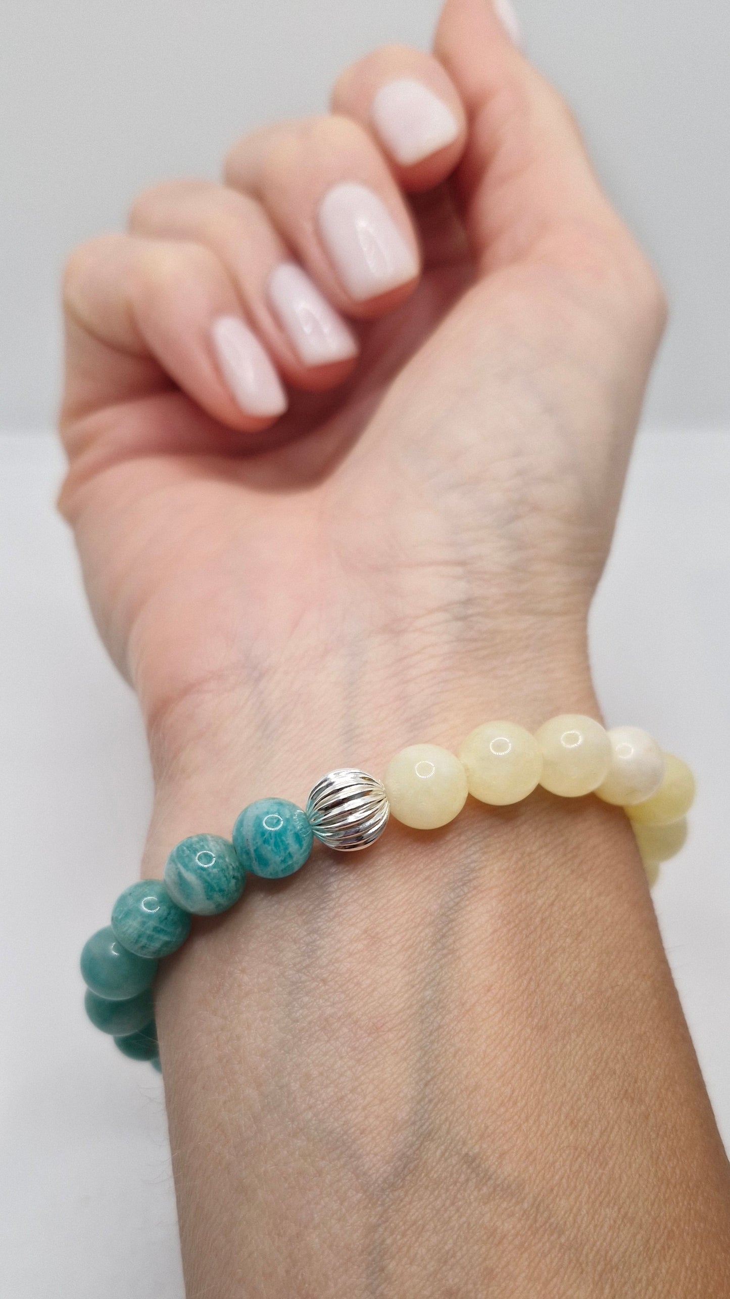 Bracelet with yellow and green beads on a wrist against a white background