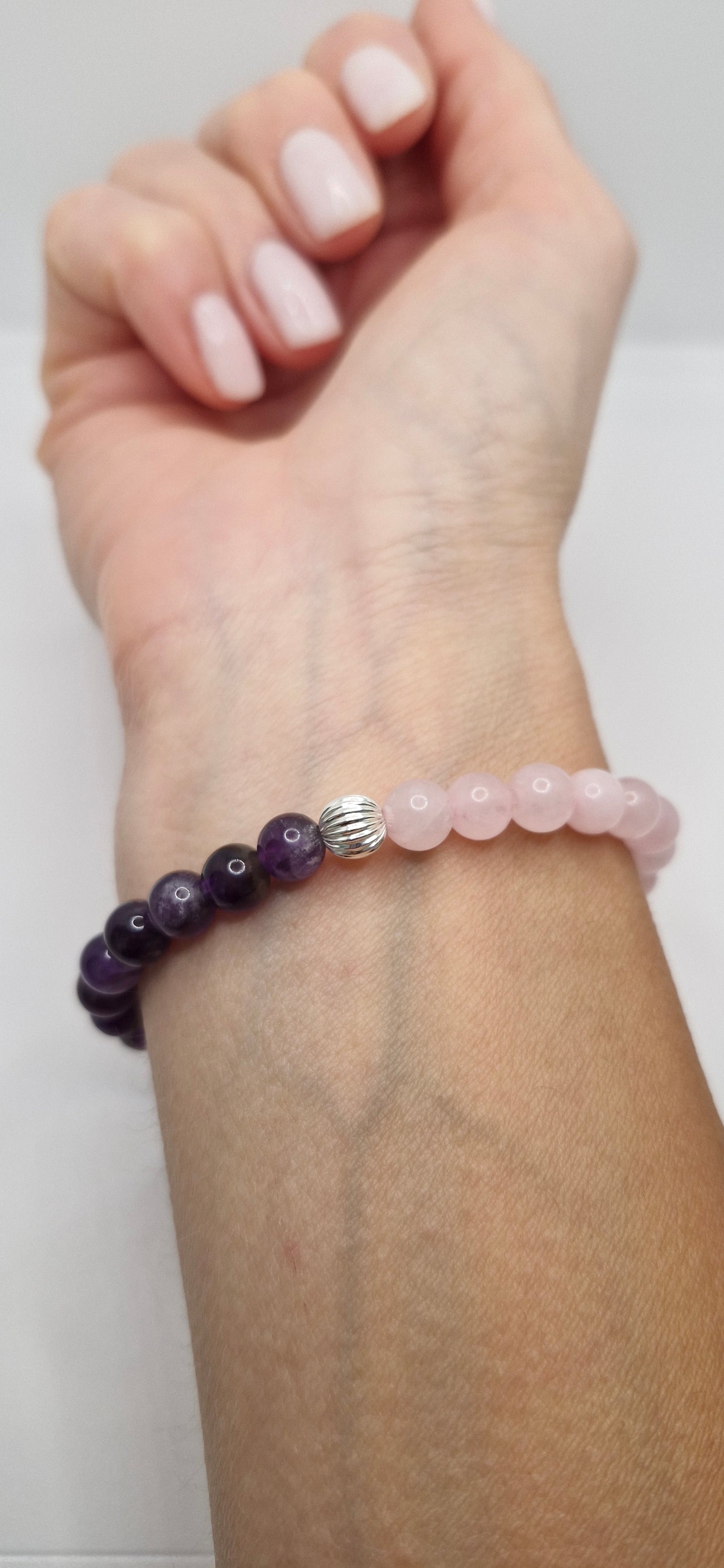 Hand wearing a beaded bracelet with a plain background