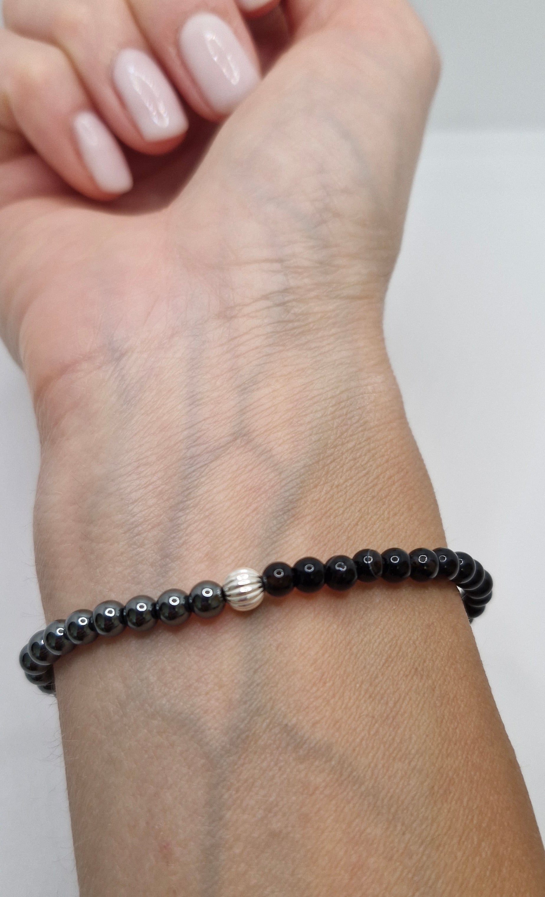 Black beaded bracelet on a wrist with a neutral background