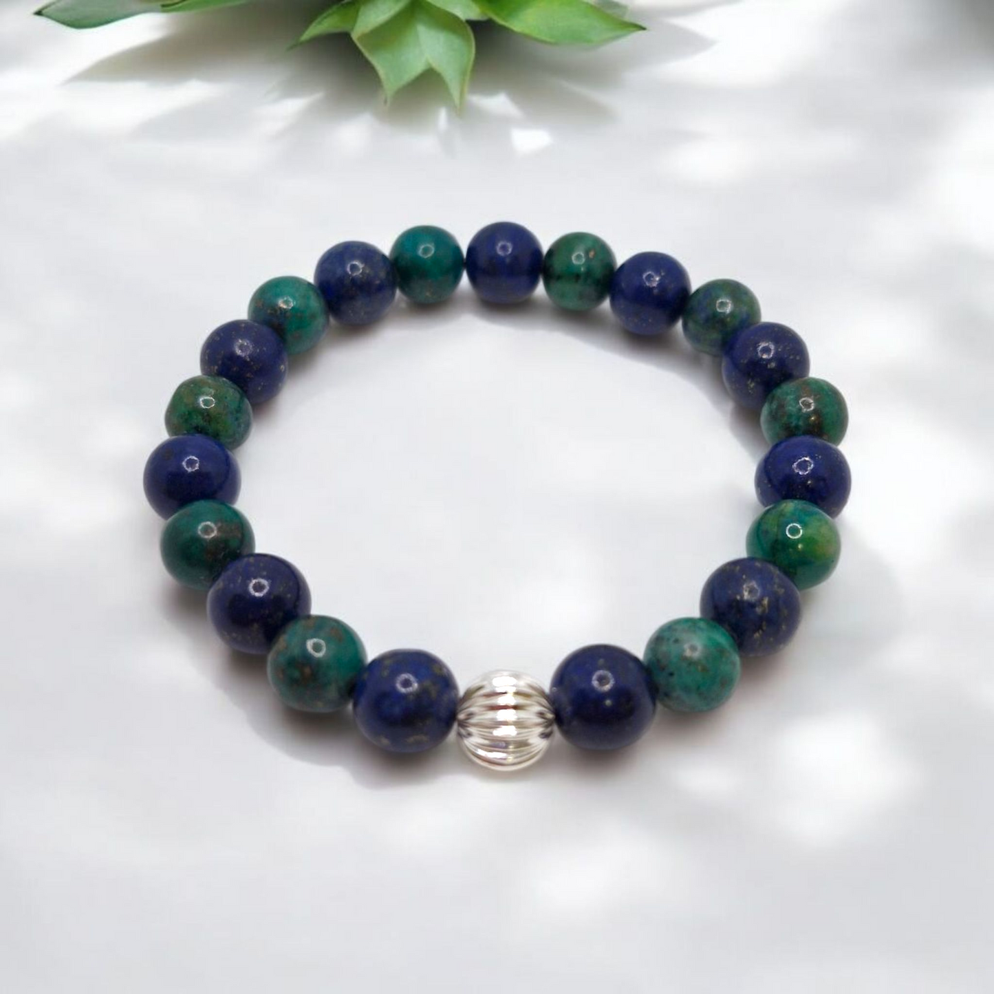 Close-up of blue and green gemstones with a single sterling silver corrugated bead, showing polished natural textures and craftsmanship.