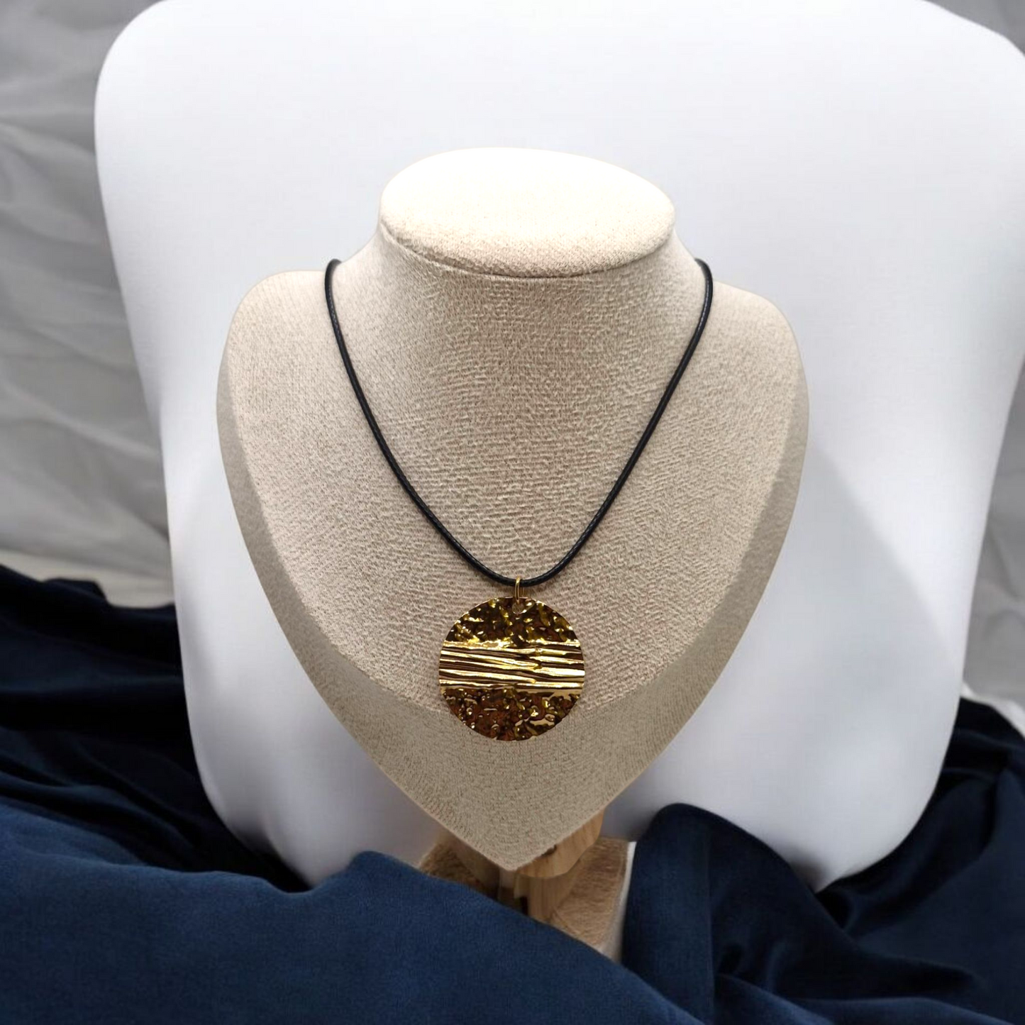 Necklace with a gold pendant on a mannequin bust against a neutral background