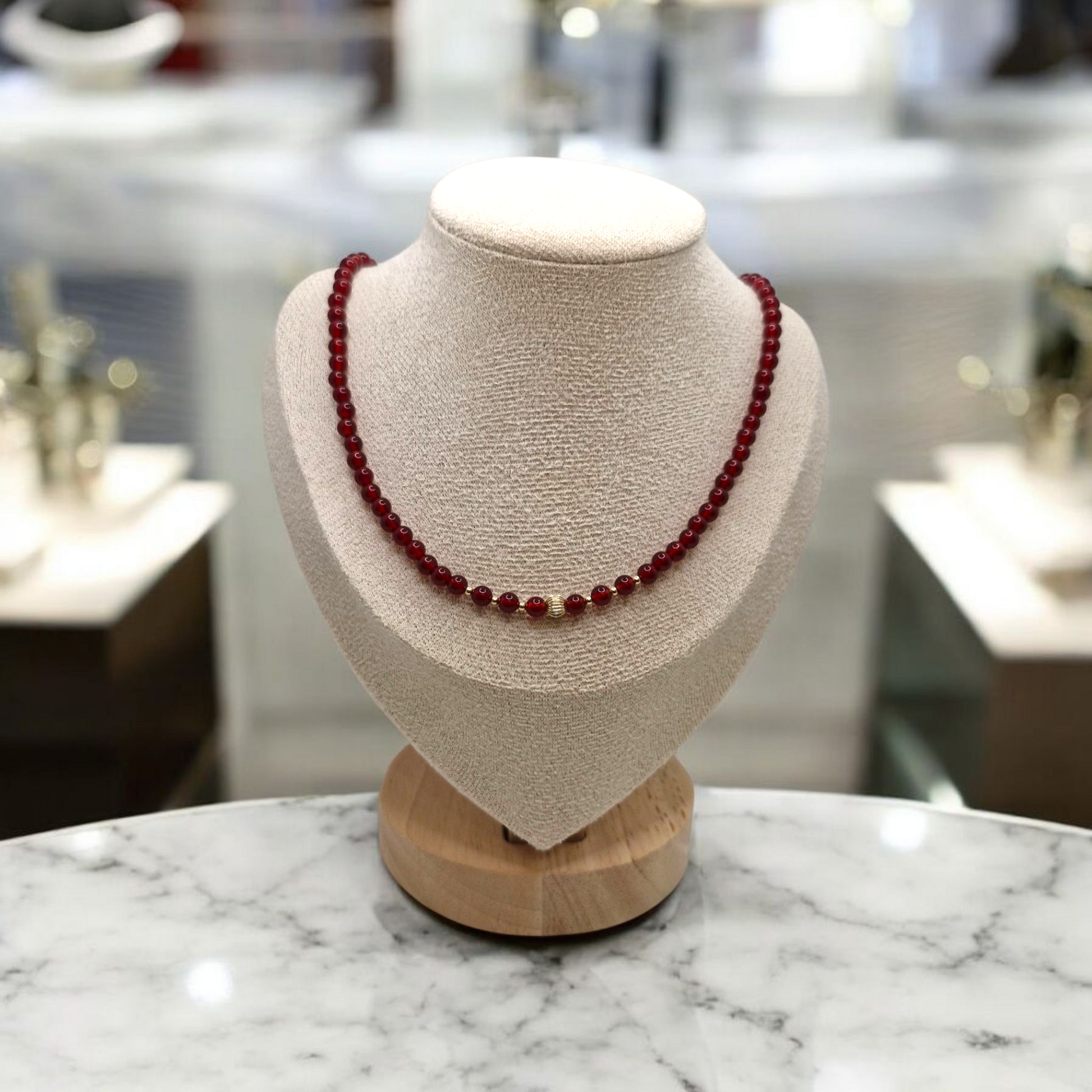 Red beaded necklace on a mannequin bust with a blurred background
