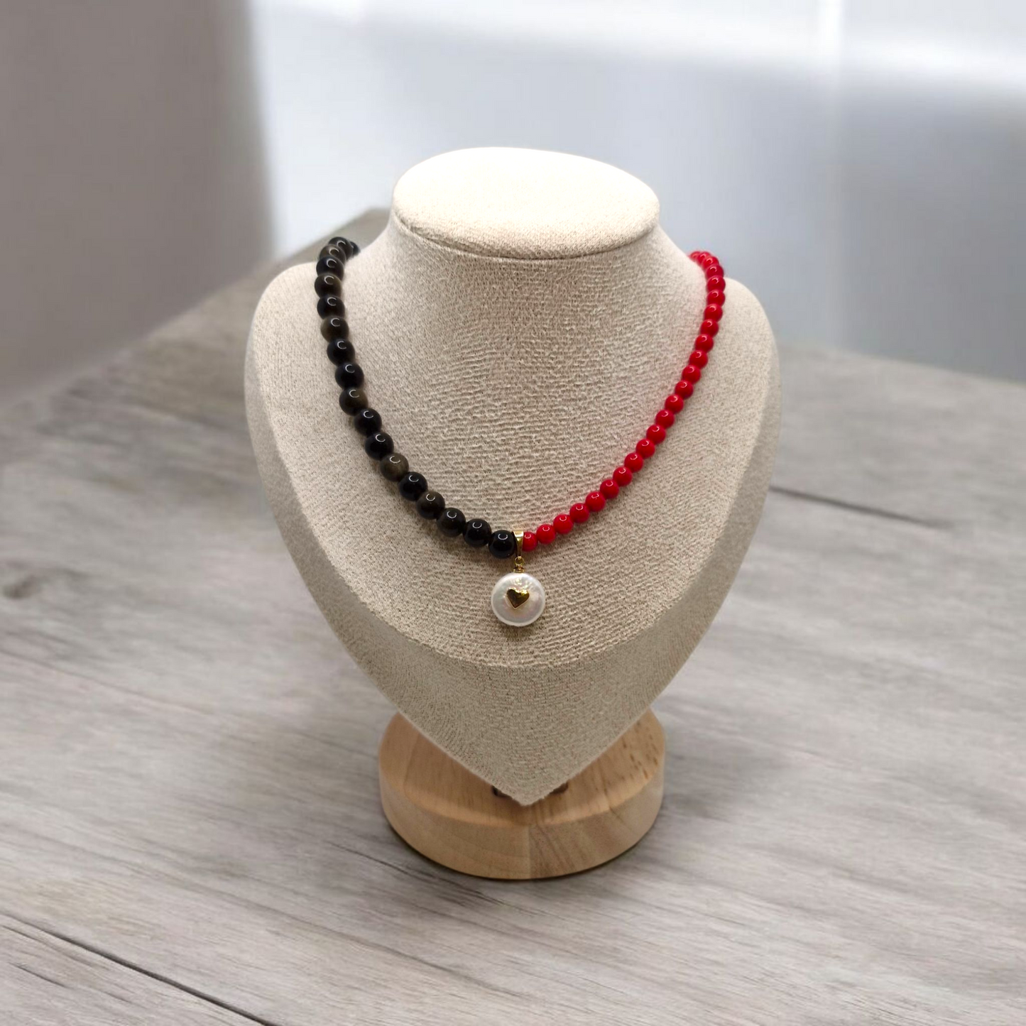 Necklace with black and red beads on a mannequin bust against a neutral background