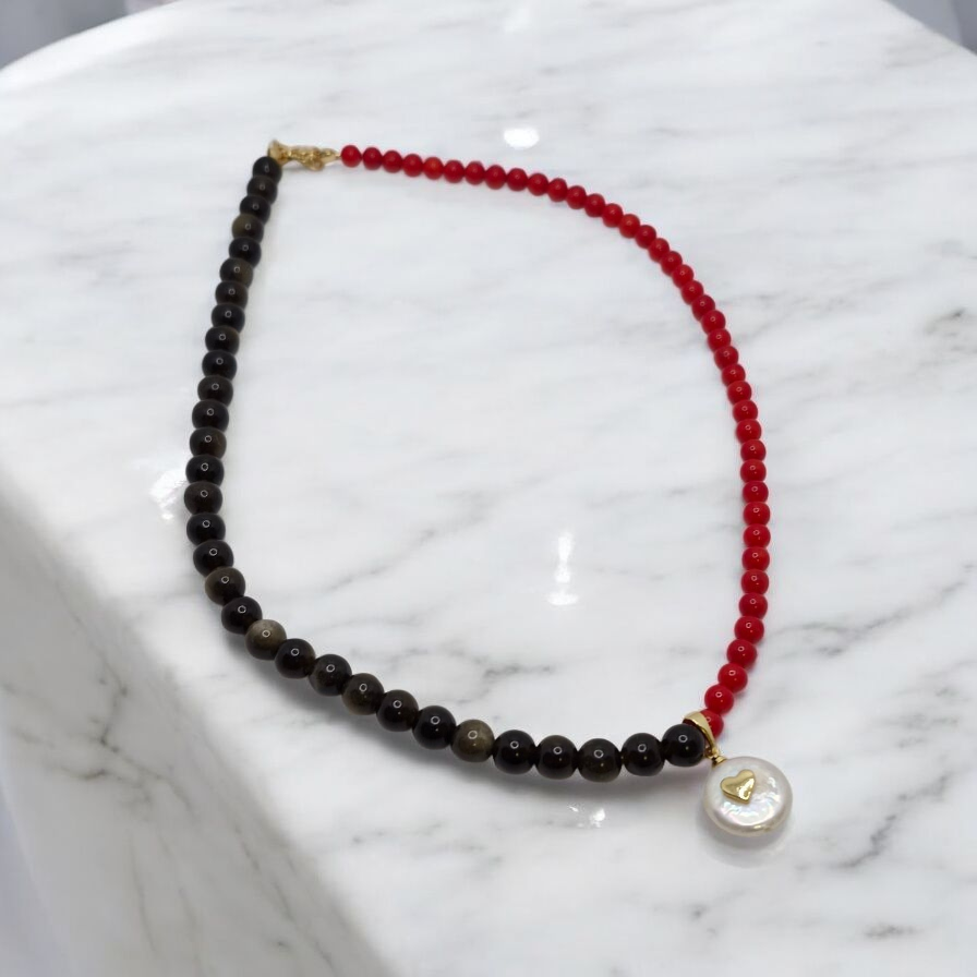 Necklace with black and red beads on a marble surface