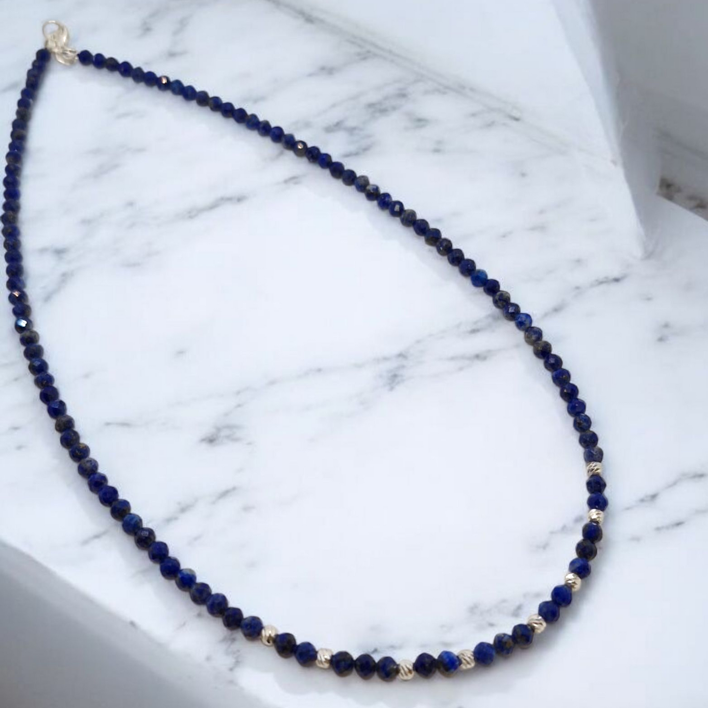 Blue beaded necklace on a marble surface