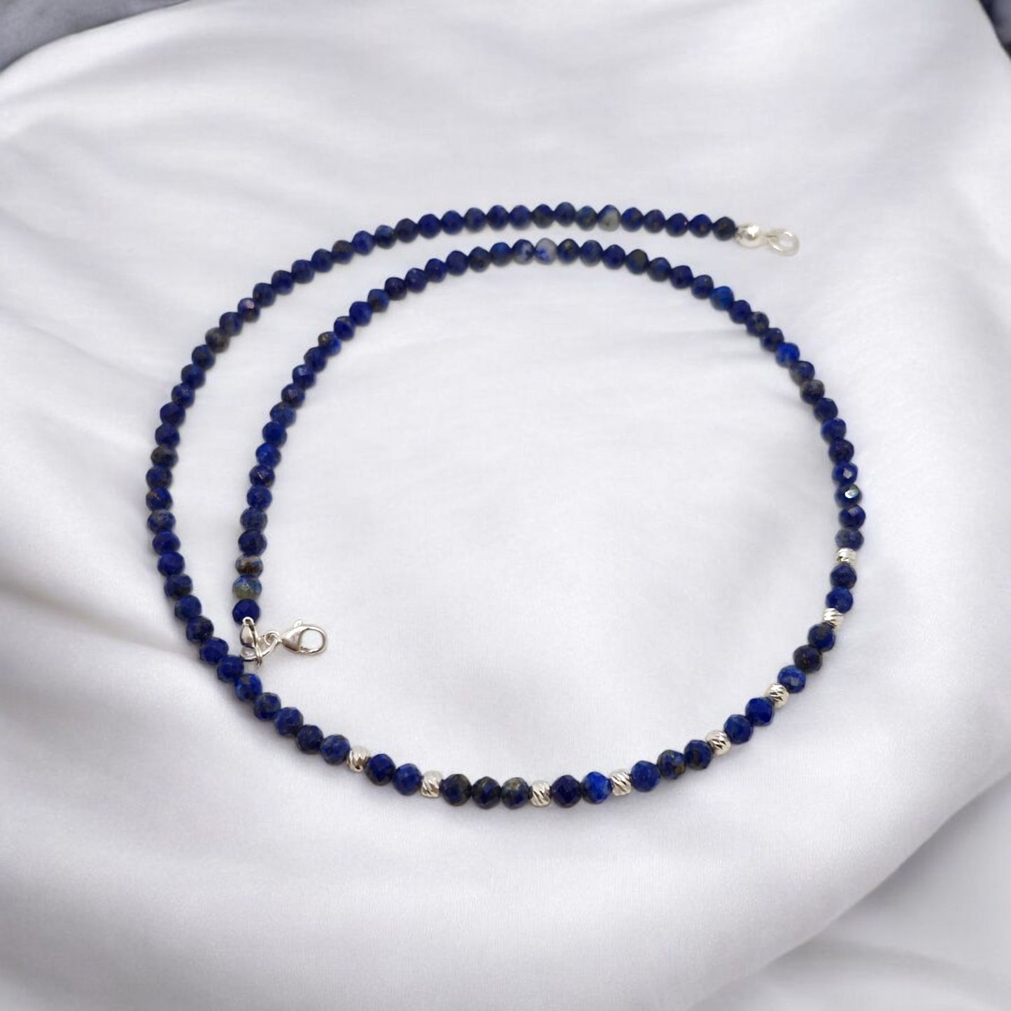 Blue beaded necklace on a white fabric background