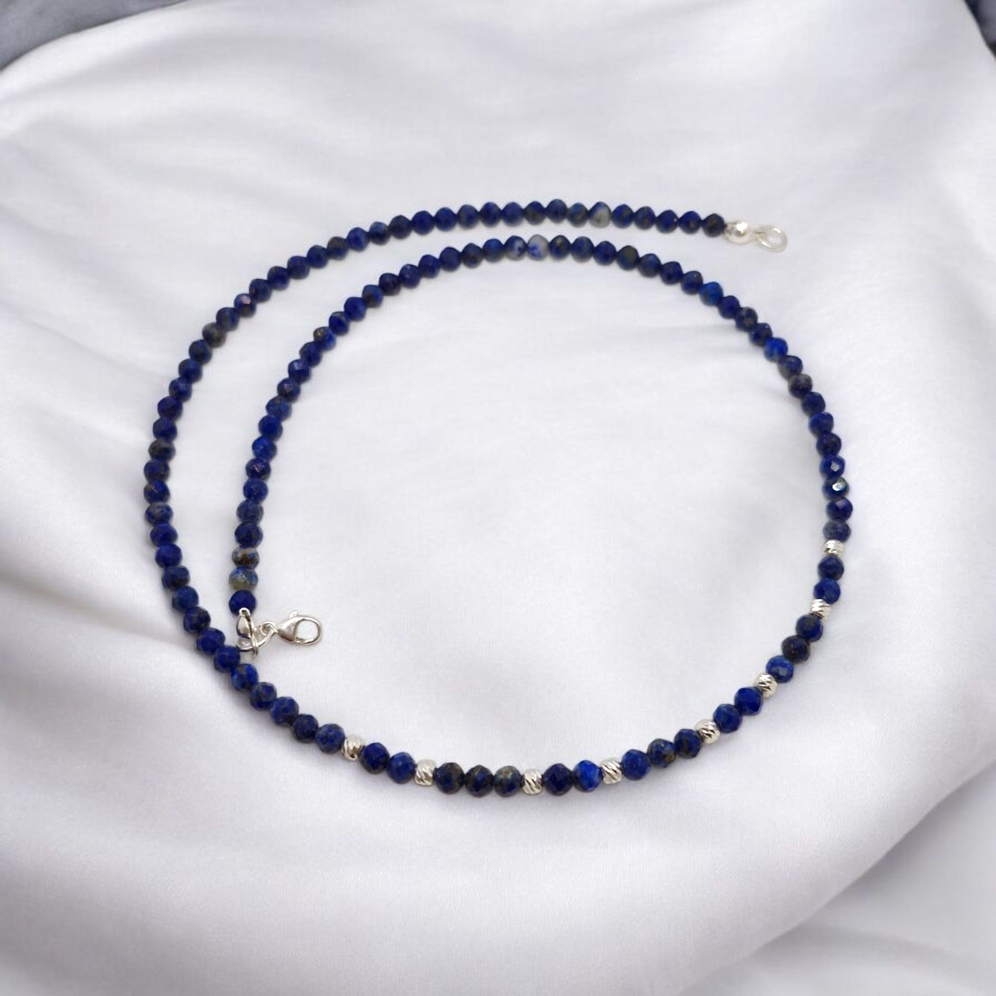 Blue beaded necklace on a white fabric background