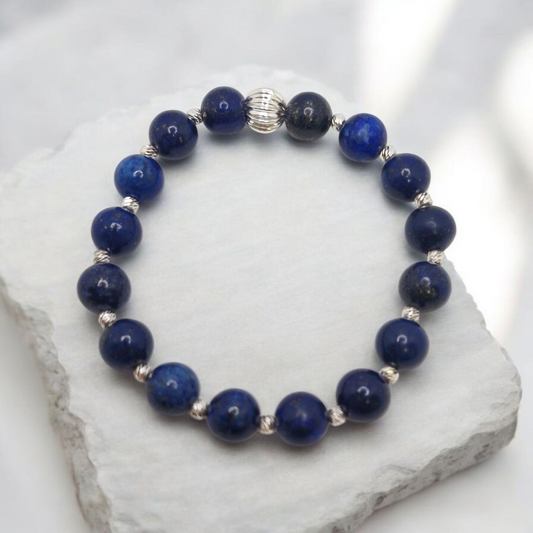 Blue beaded bracelet with silver accents on a white stone surface