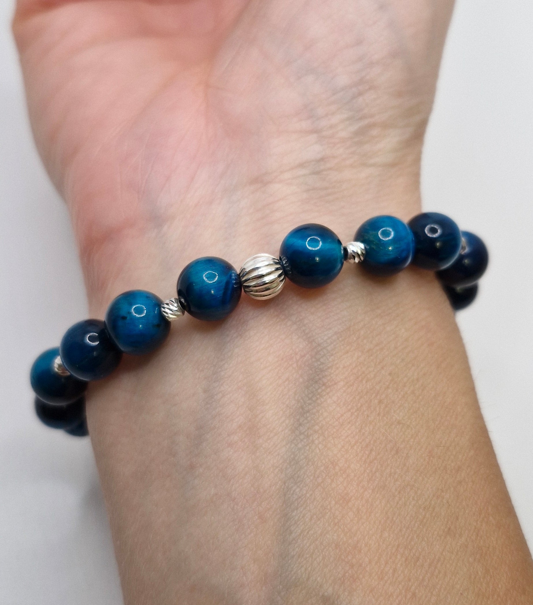 Blue beaded bracelet on a wrist against a white background