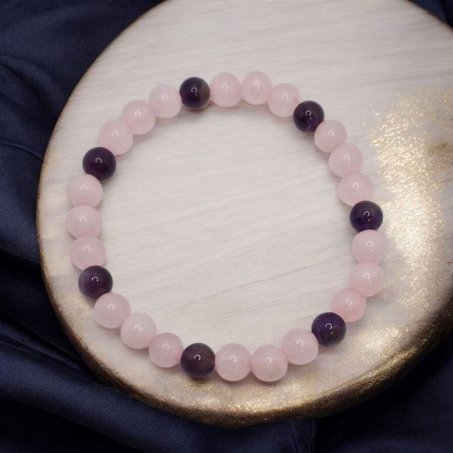 Bracelet with pink and purple beads on a round wooden surface