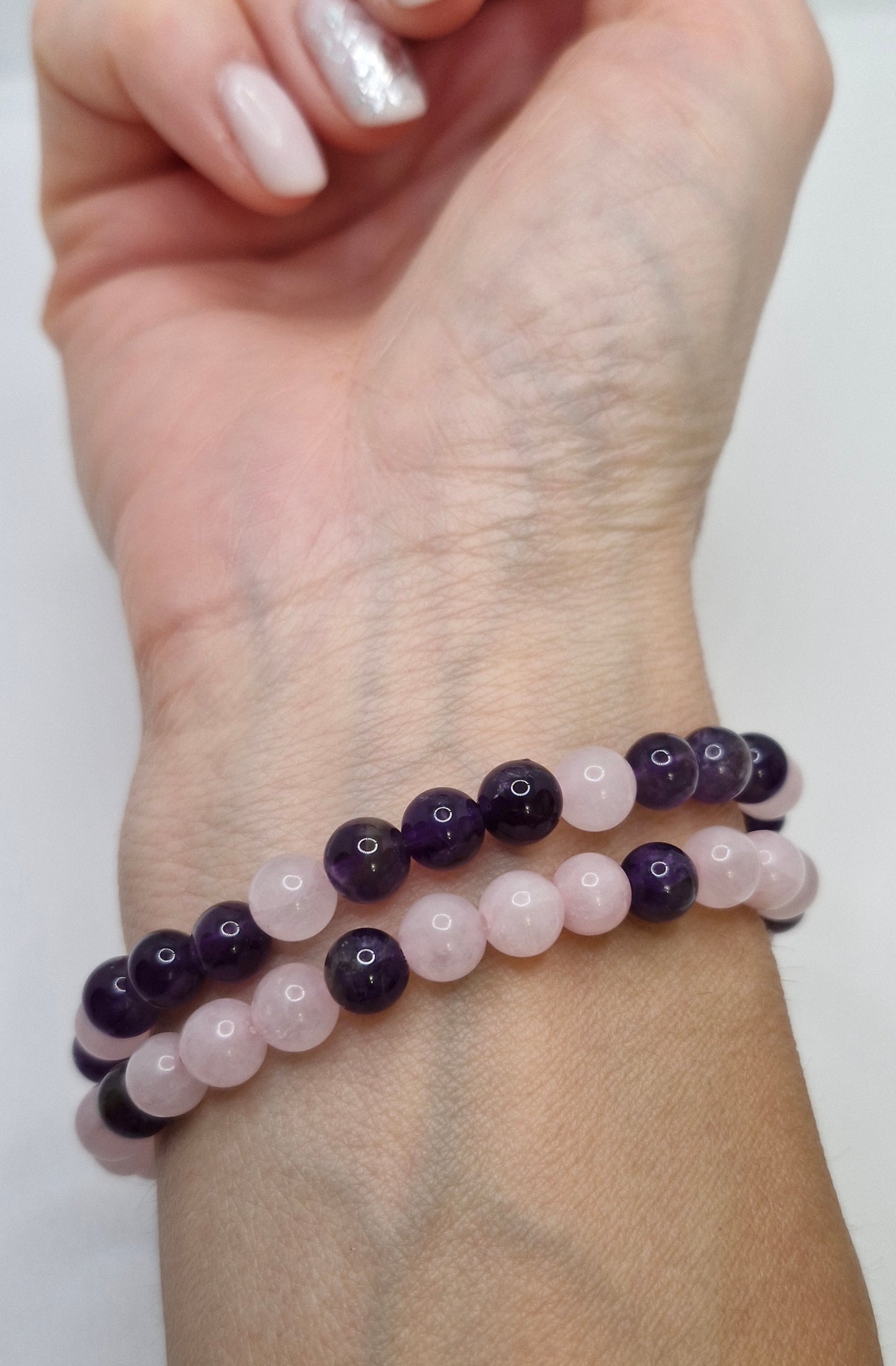 Two beaded bracelets on a wrist against a white background