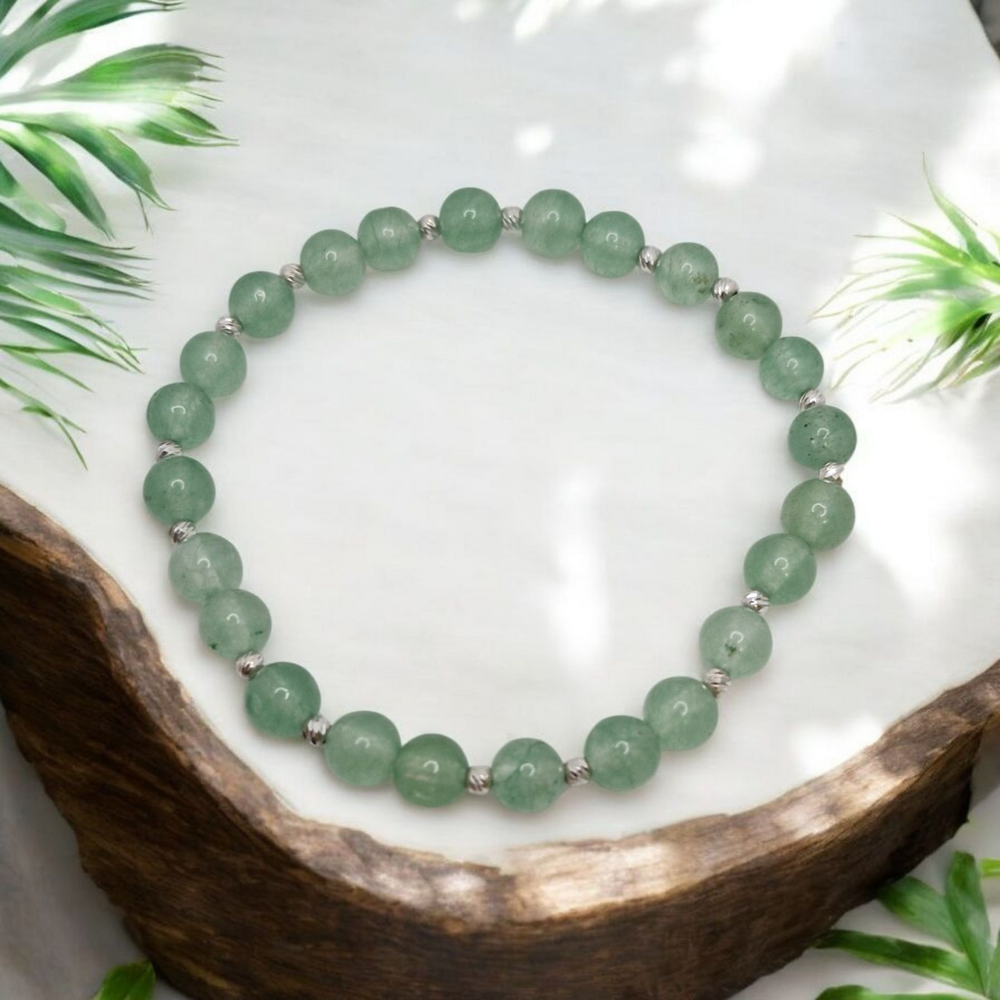 Green beaded bracelet on a white surface with natural elements