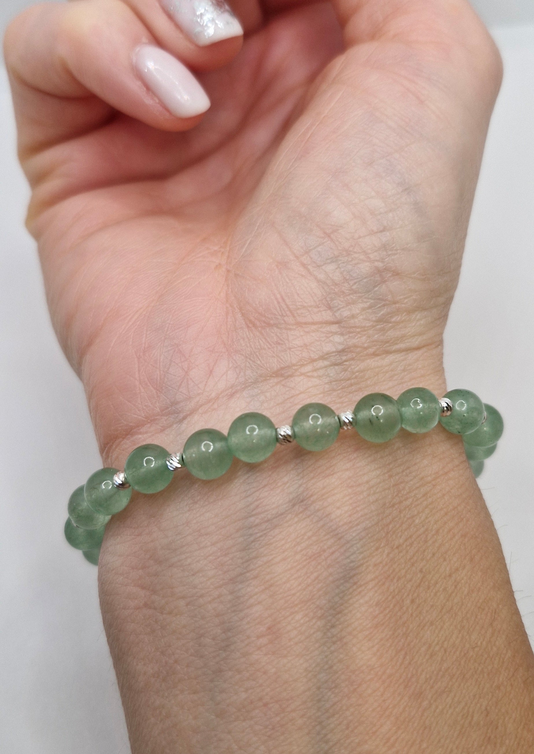 Green beaded bracelet on a wrist with a white background