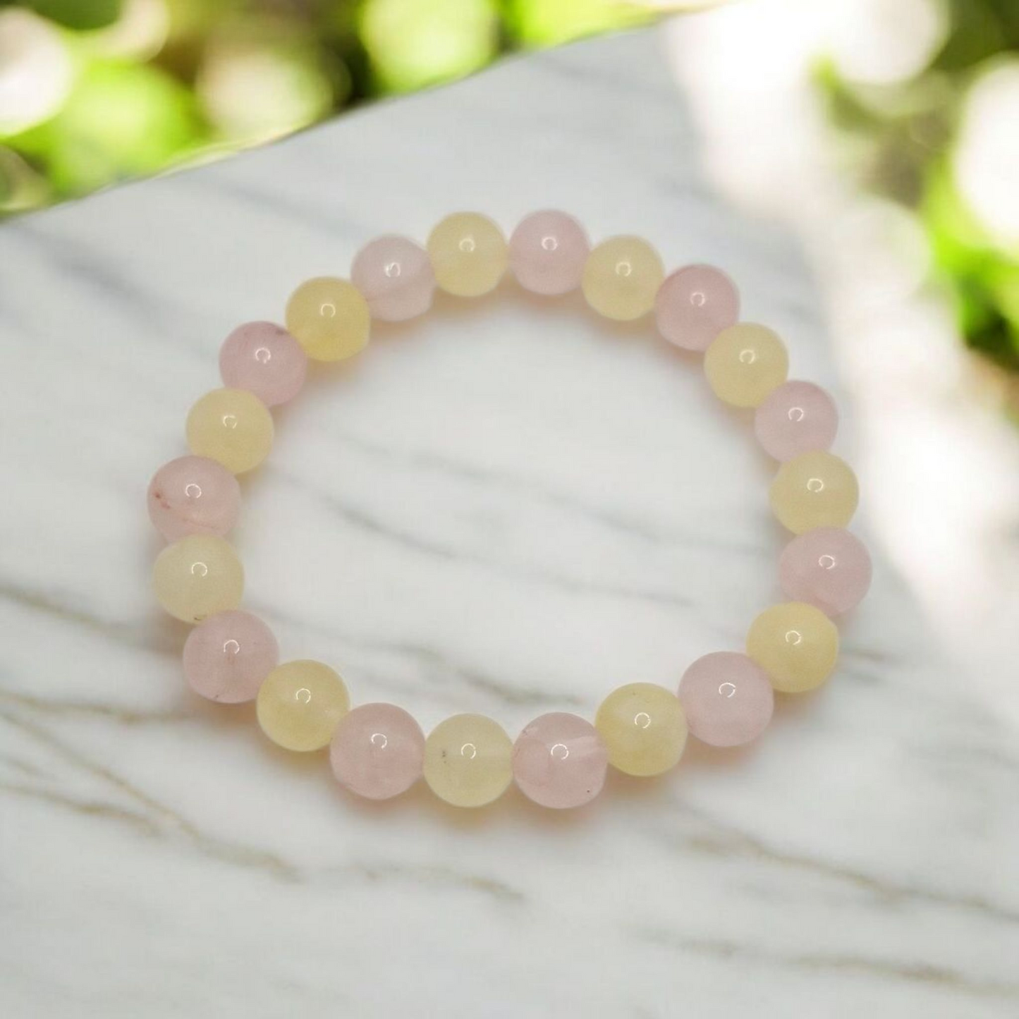 Beaded bracelet with pink and yellow beads on a white surface with a blurred natural background