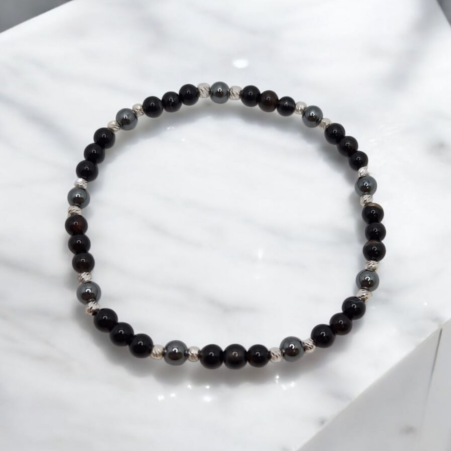 Black beaded bracelet on a white marble surface