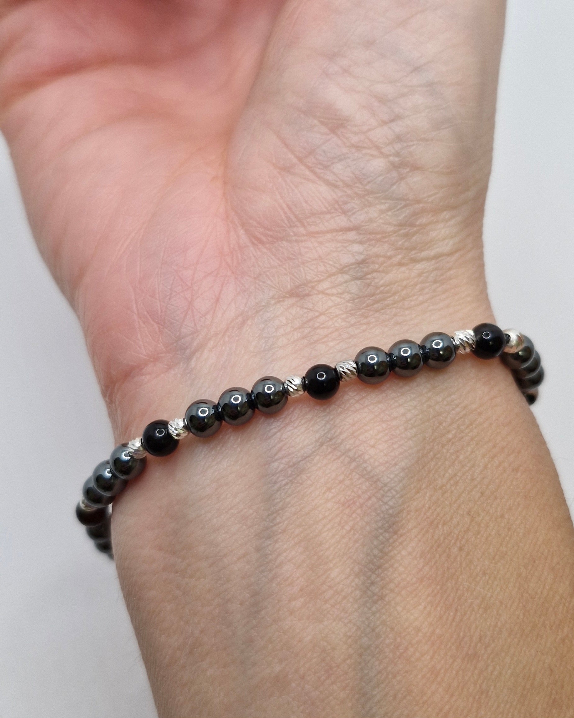 Black beaded bracelet on a wrist against a white background