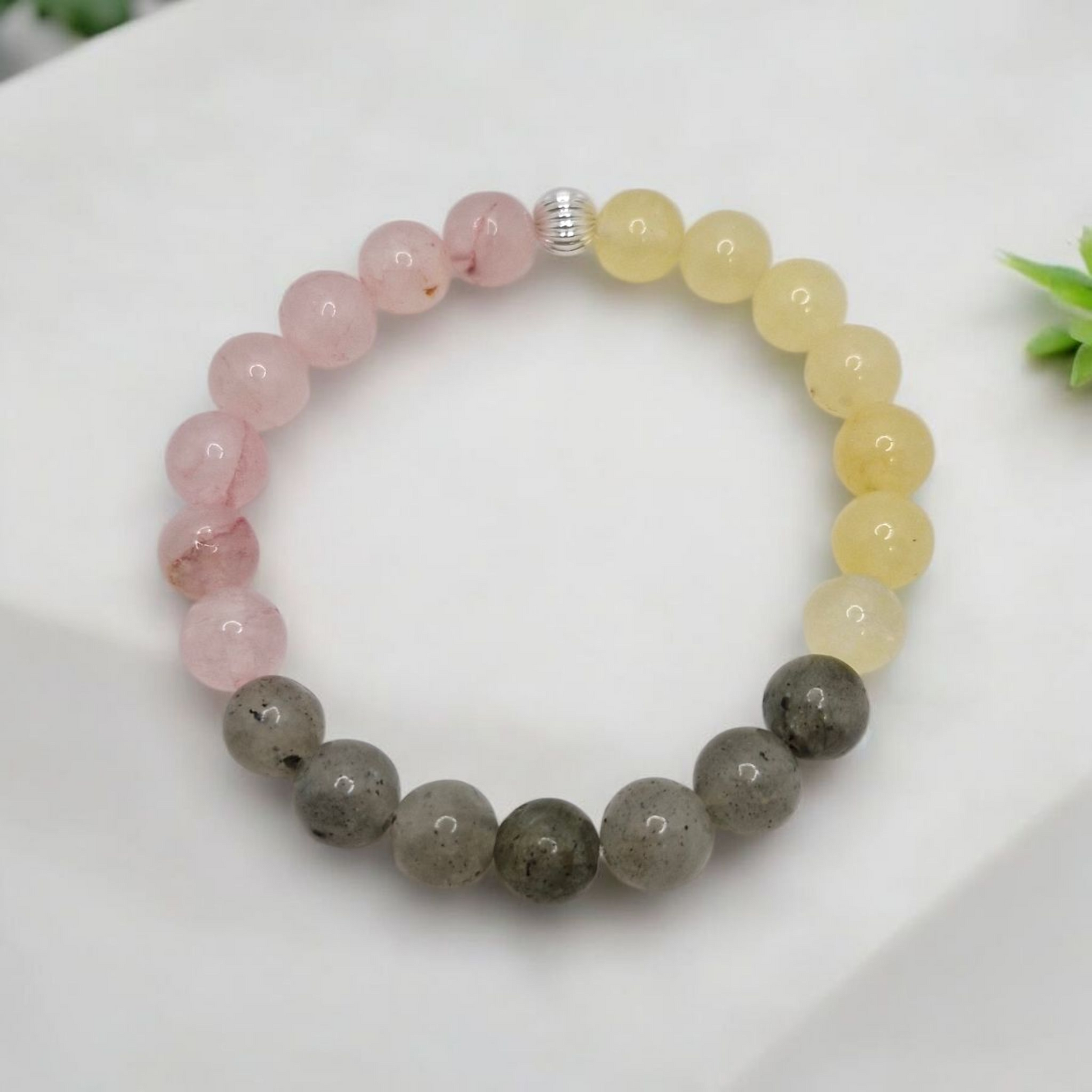Multicolored beaded bracelet on a white surface with greenery in the background