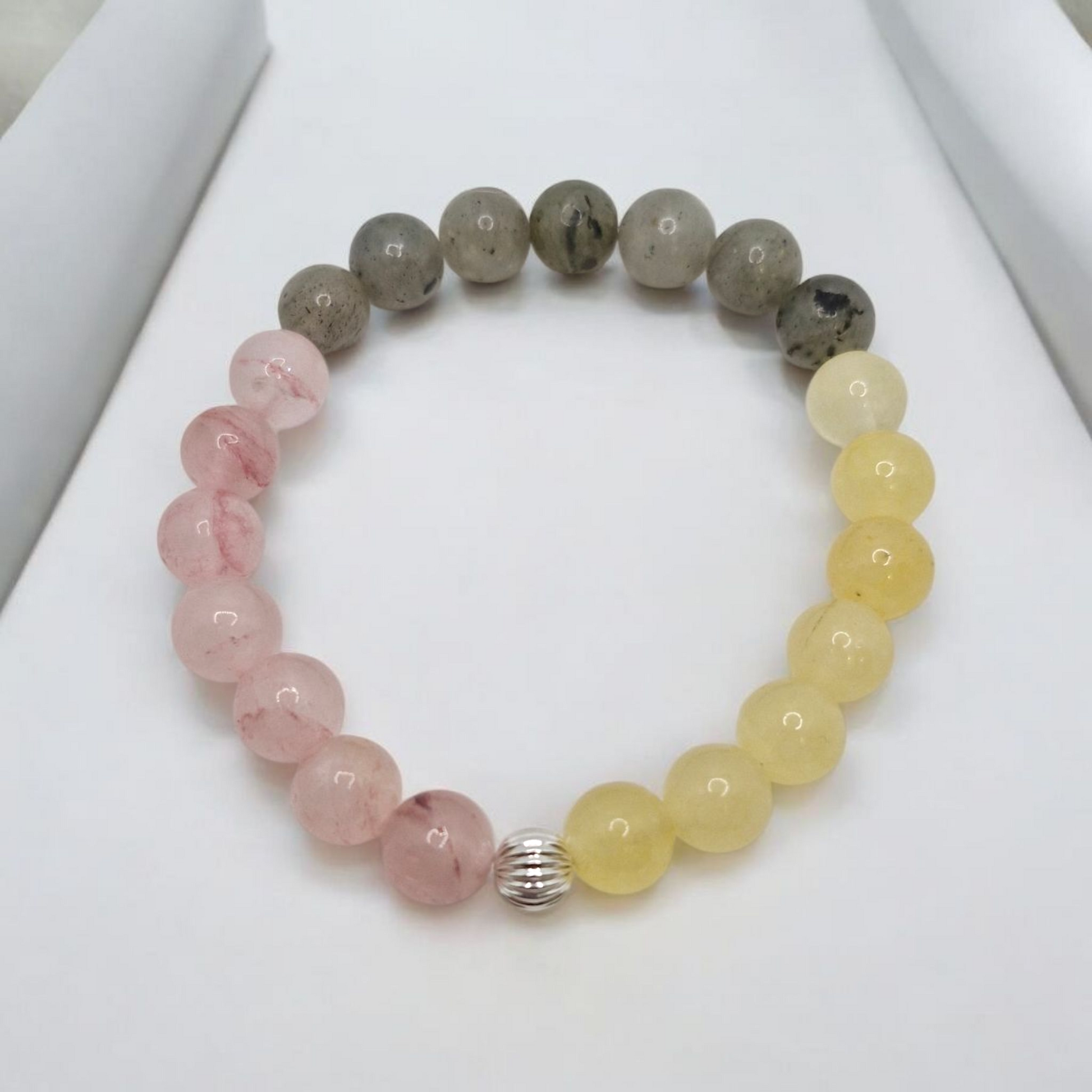 Beaded bracelet with pink, yellow, and gray beads on a white surface