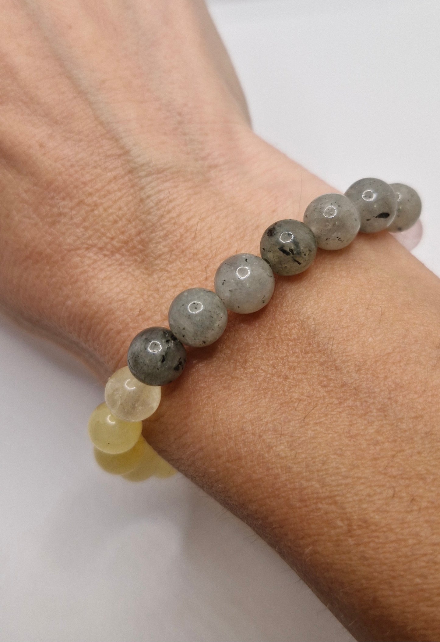 Bracelet with gray and yellow beads on a wrist against a white background