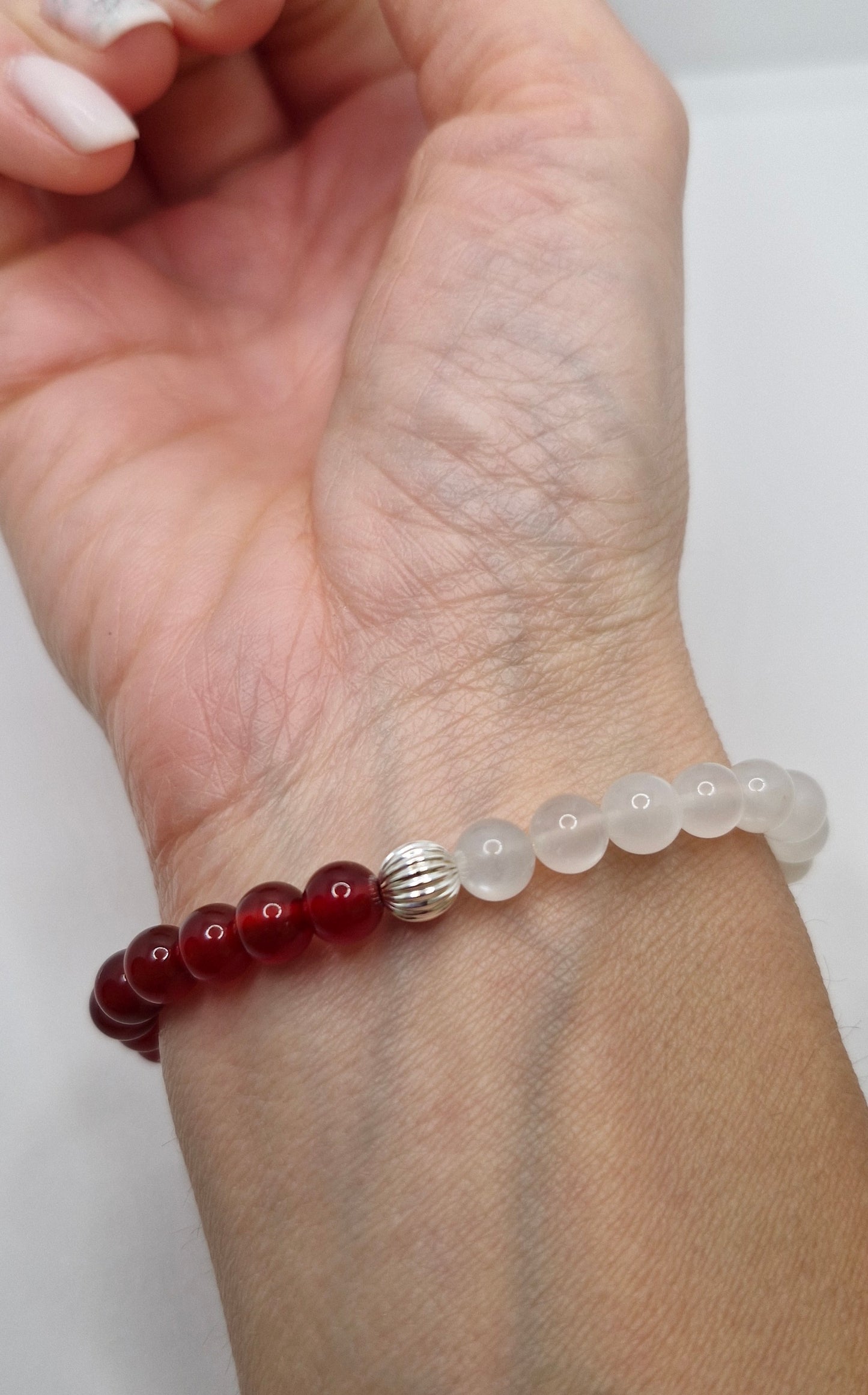 Bracelet with red and clear beads on a wrist against a white background
