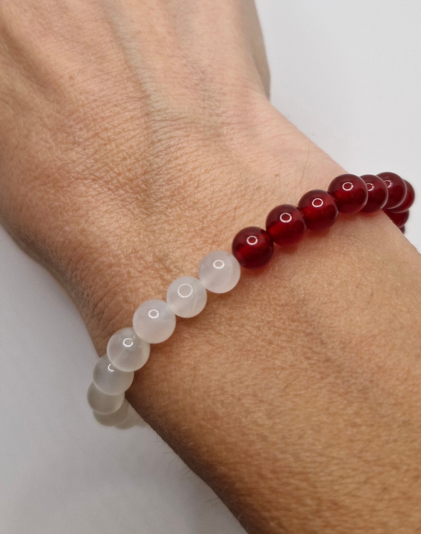 Beaded bracelet with red and clear beads on a wrist against a white background