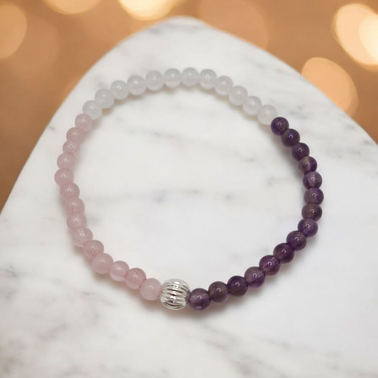 Beaded bracelet with pink and purple beads on a marble surface with a blurred background