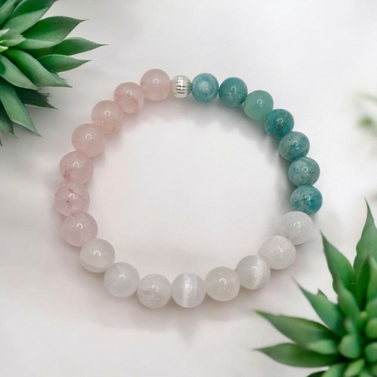 Multicolored beaded bracelet on a white background with green leaves