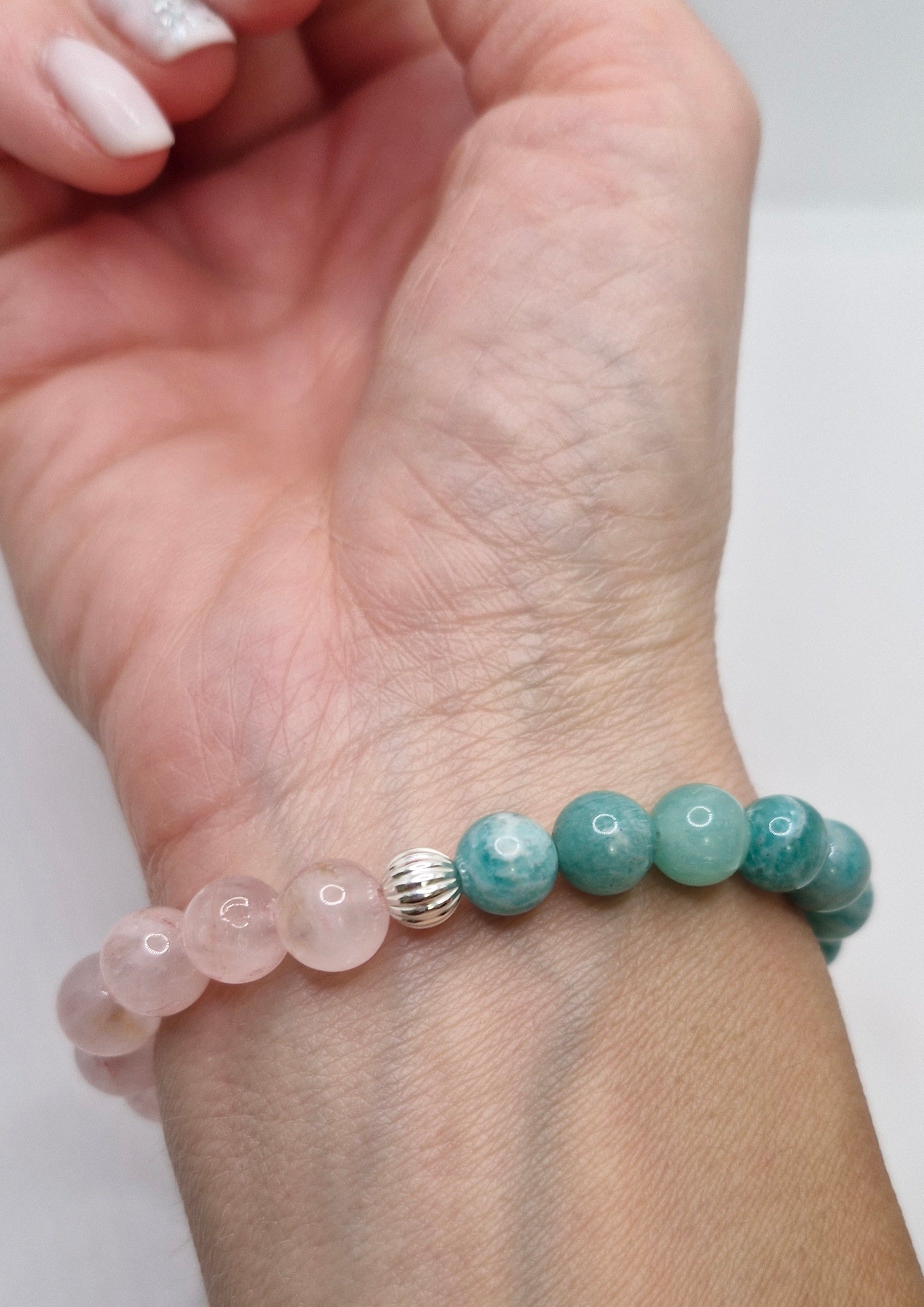 Bracelet with pink and green beads on a wrist against a white background