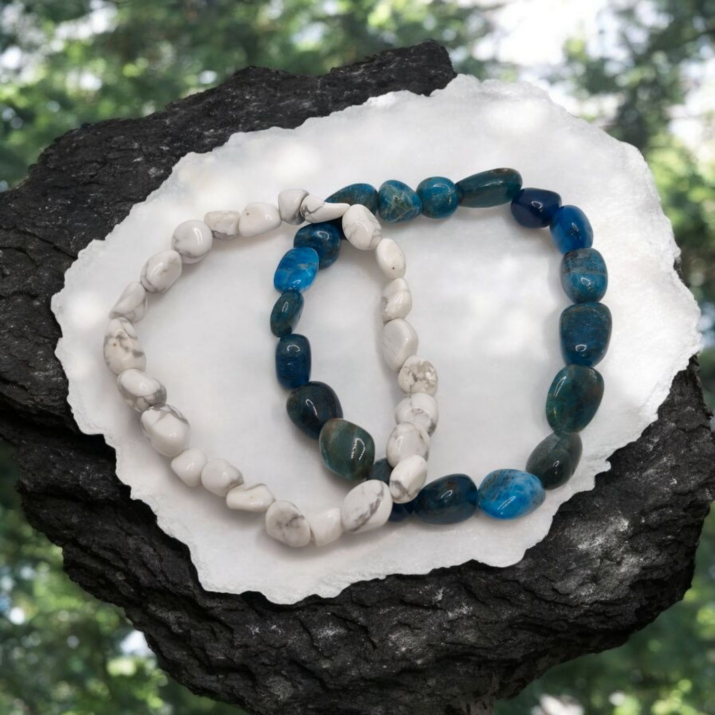 Two stone bracelets on a white shell with a natural background