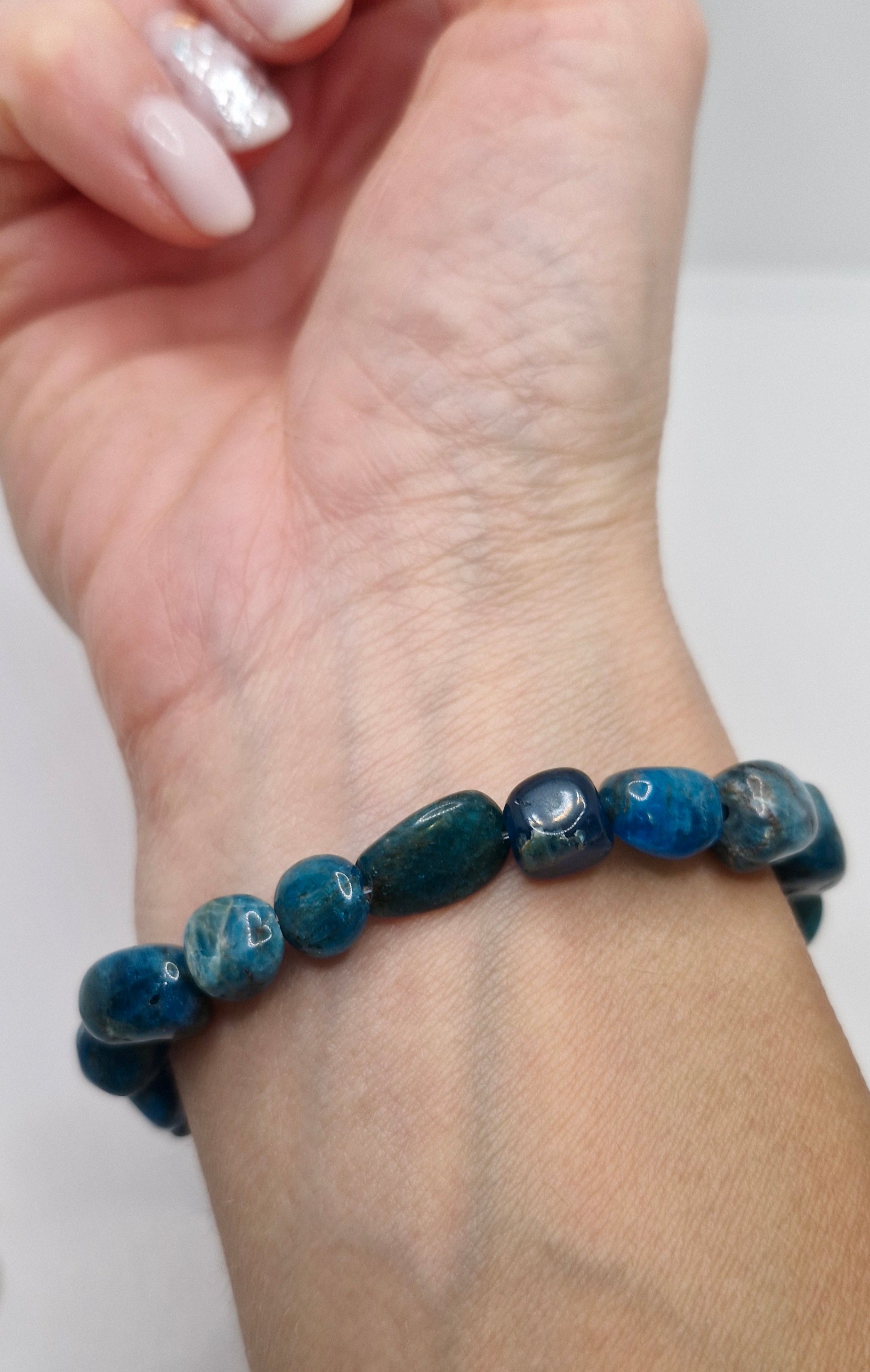 Blue beaded bracelet on a wrist with a plain background