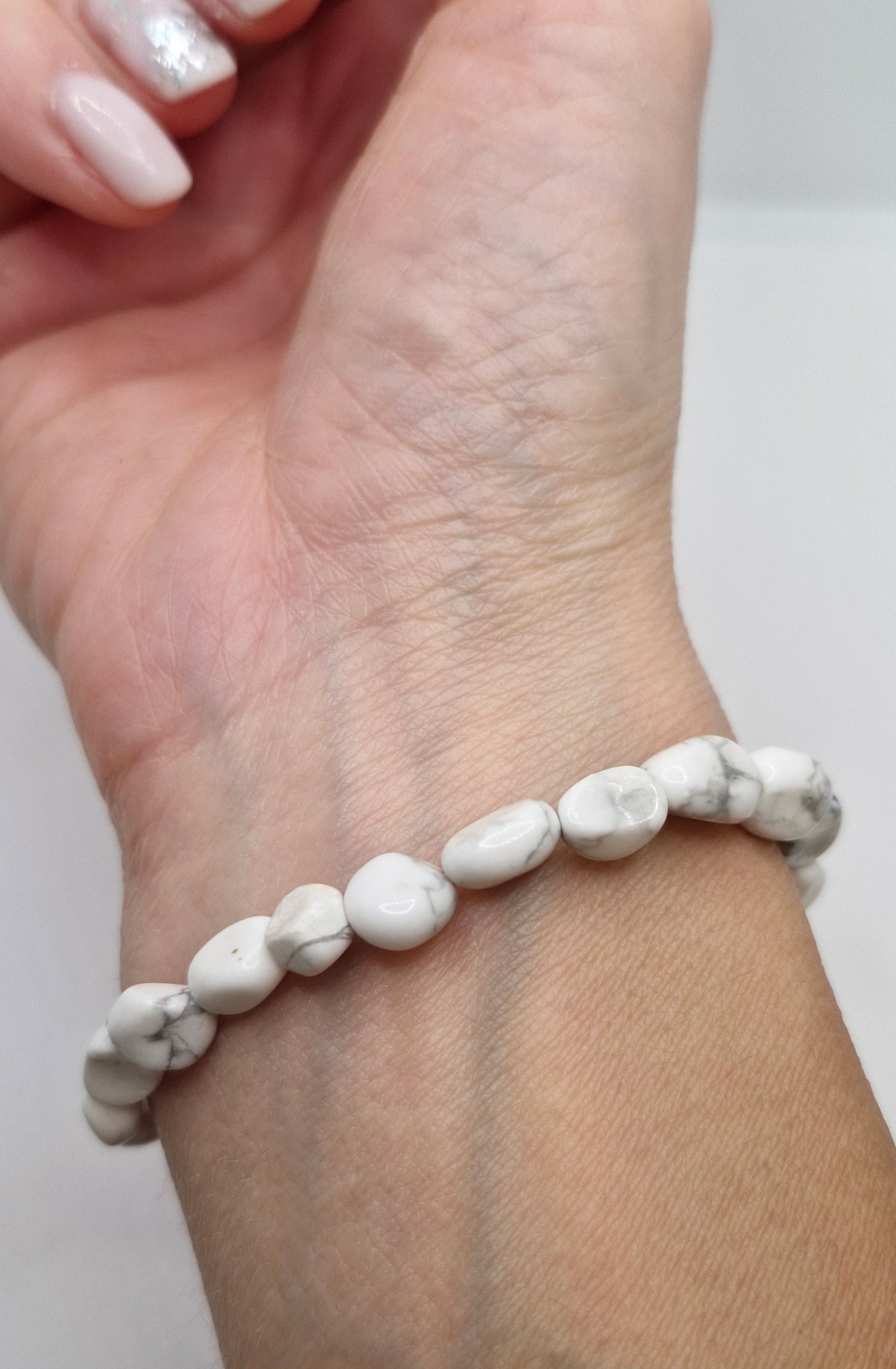 White beaded bracelet on a wrist with a plain background