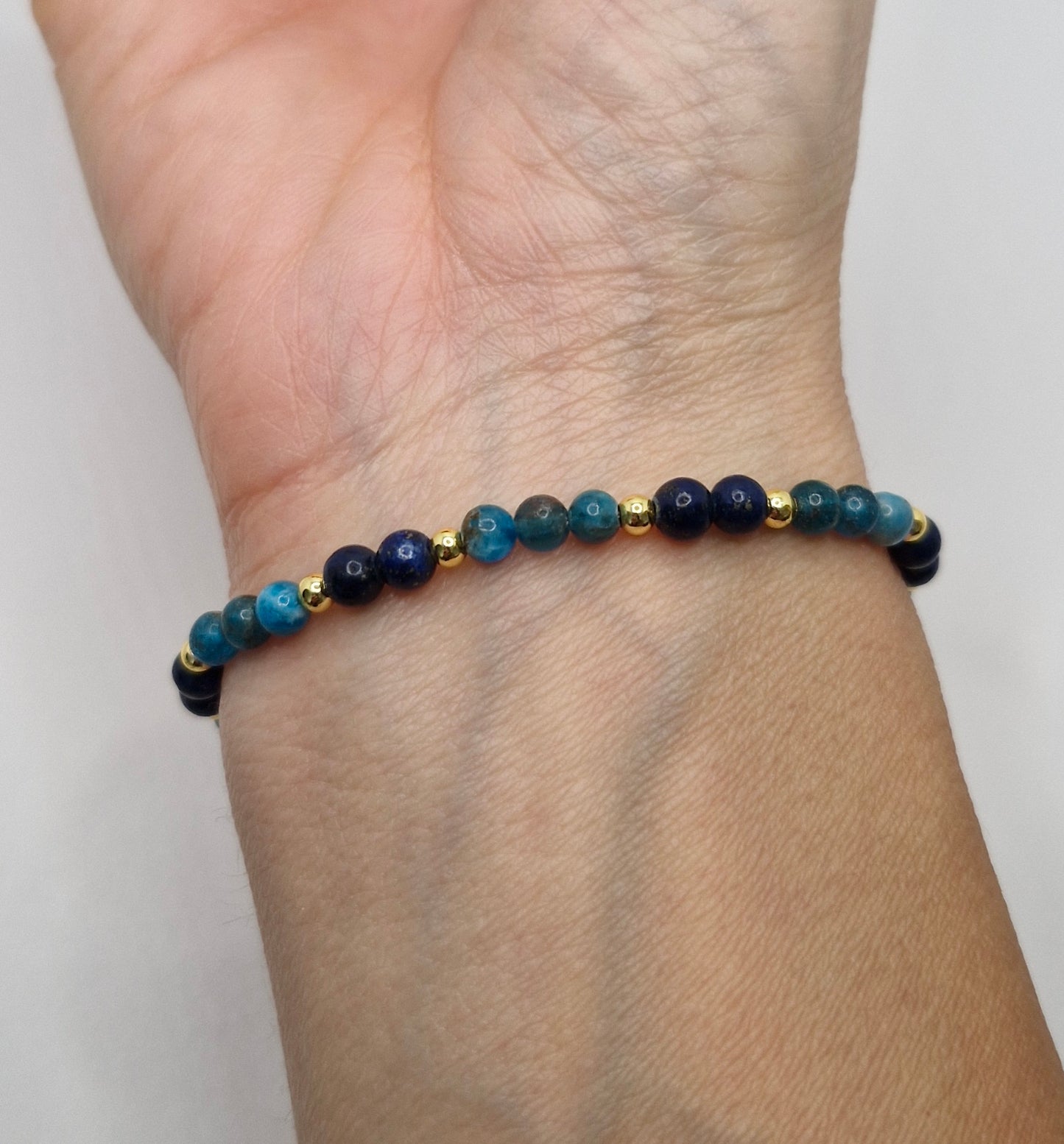 Beaded bracelet with blue and gold beads on a wrist against a white background