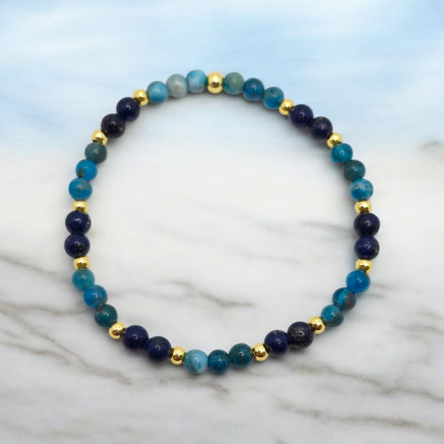 Beaded bracelet with blue and gold beads on a marble surface