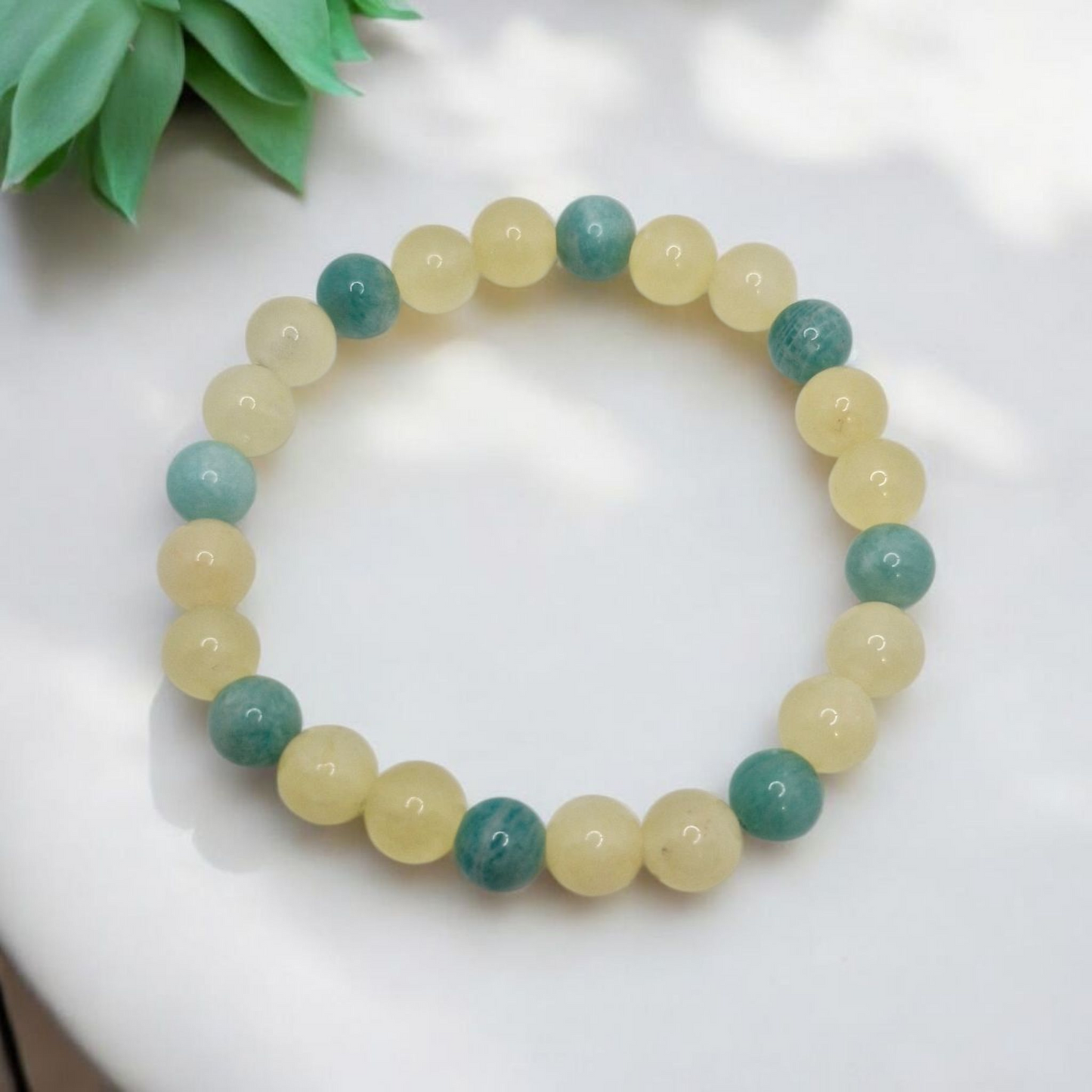 Beaded bracelet with green and beige beads on a white surface