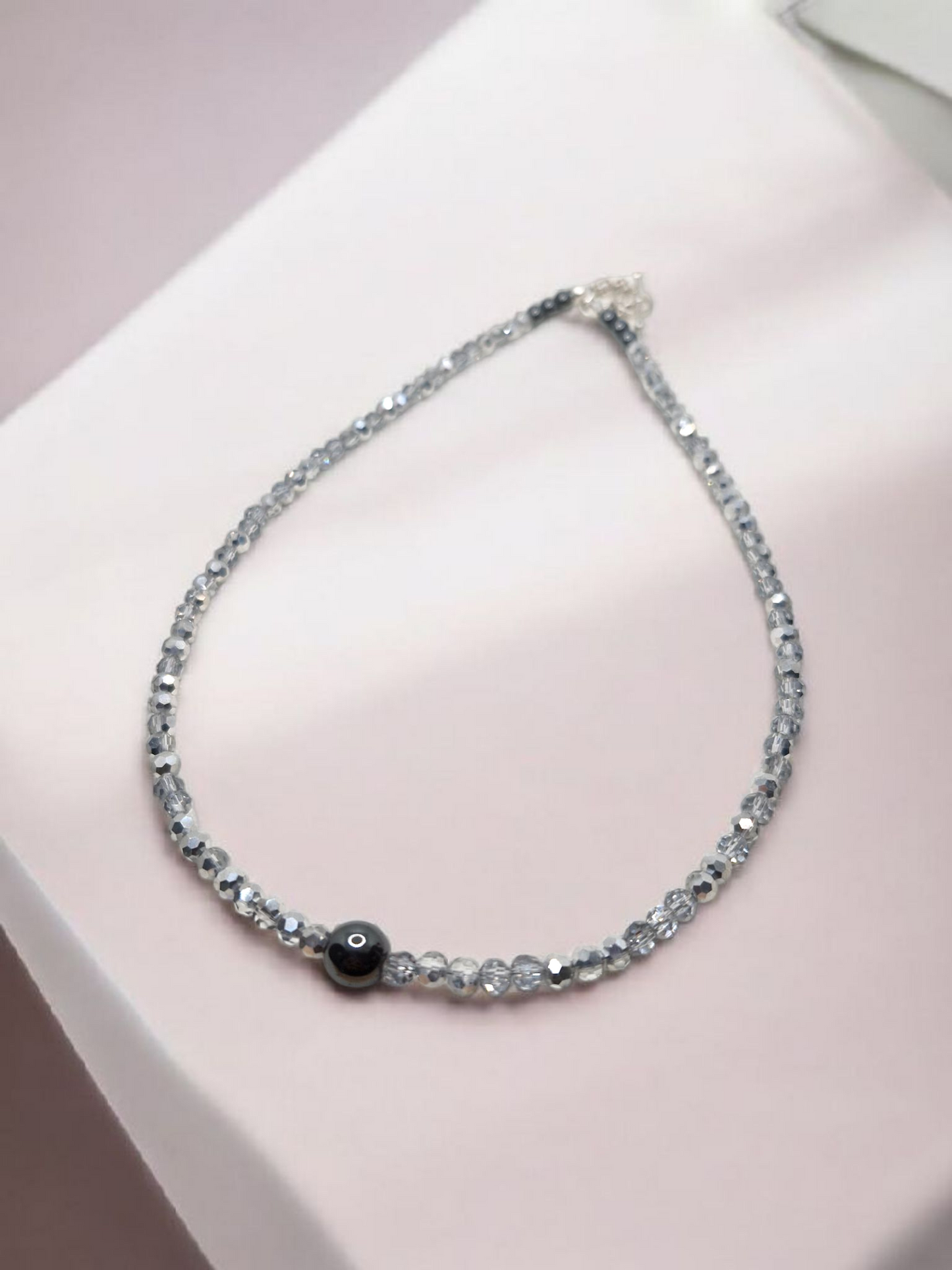 Necklace with black bead on a pink surface