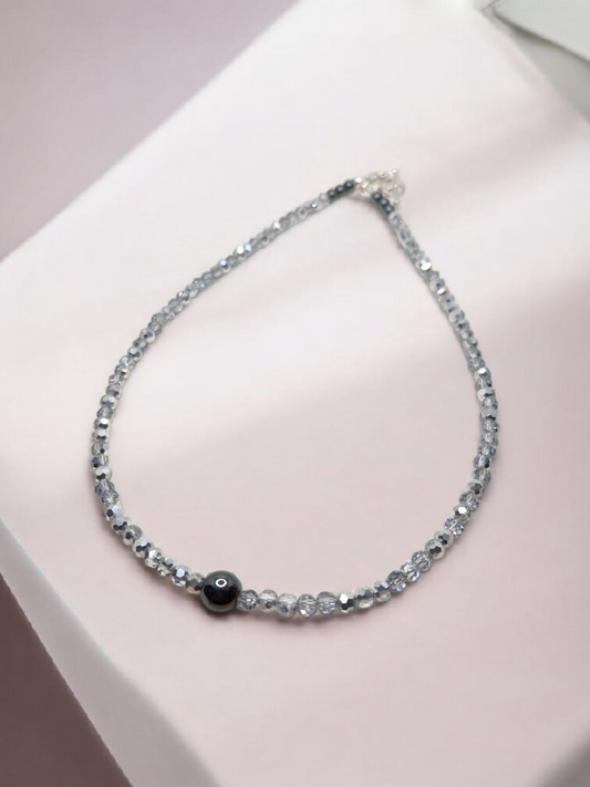 Necklace with black bead on a pink surface