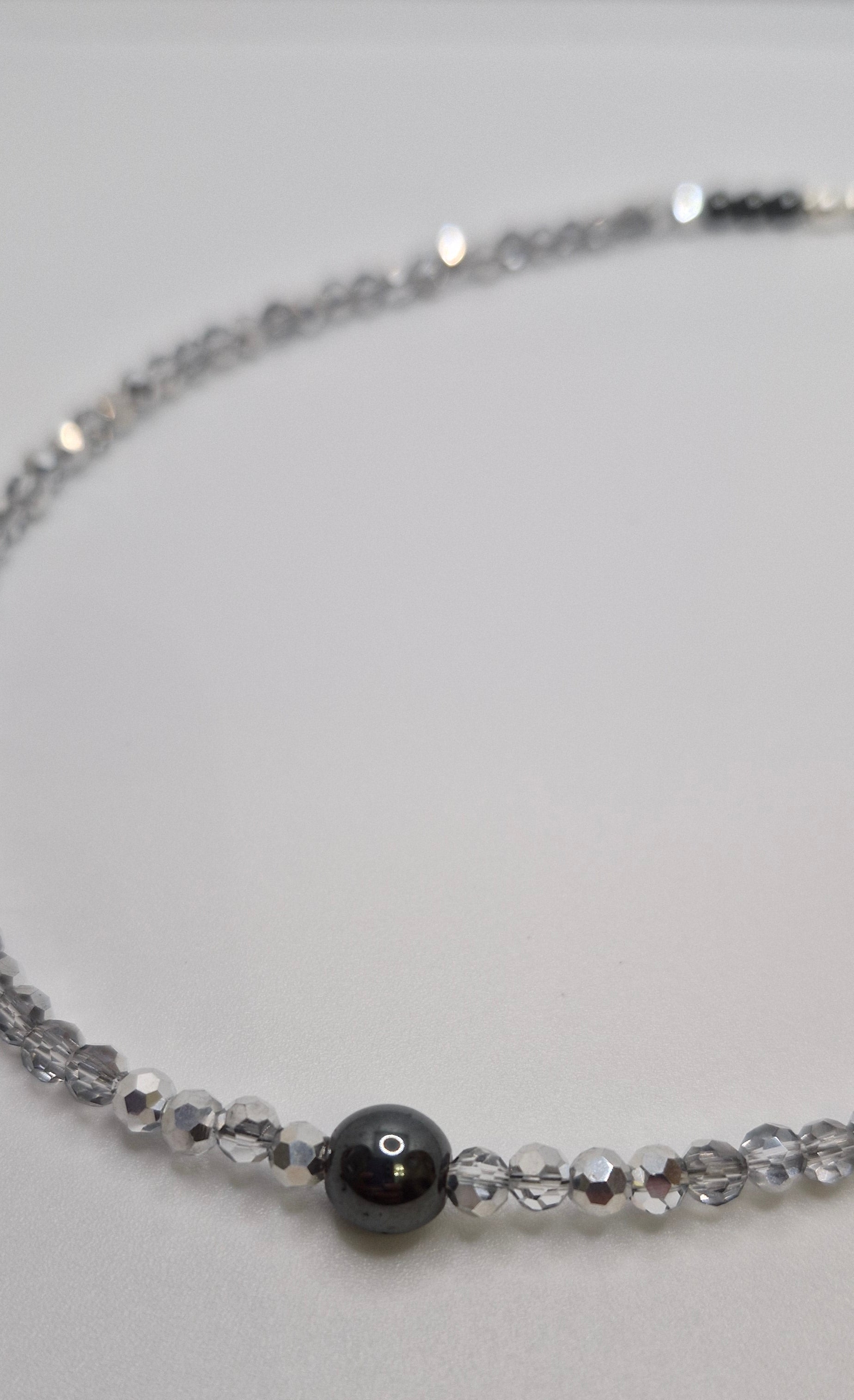 Necklace with black bead and clear beads on a light gray background