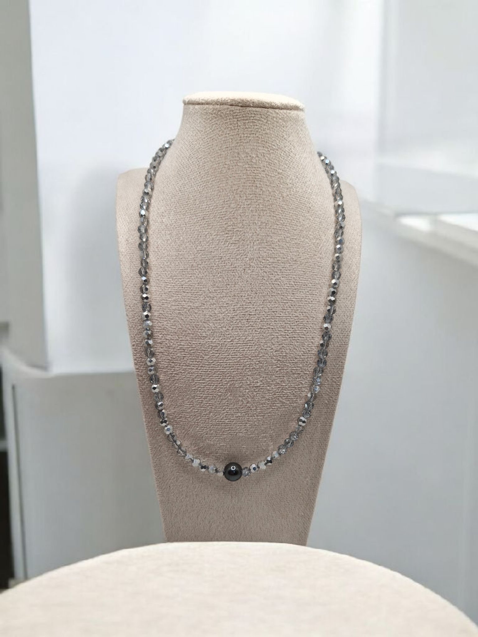 Necklace on a mannequin bust against a neutral background