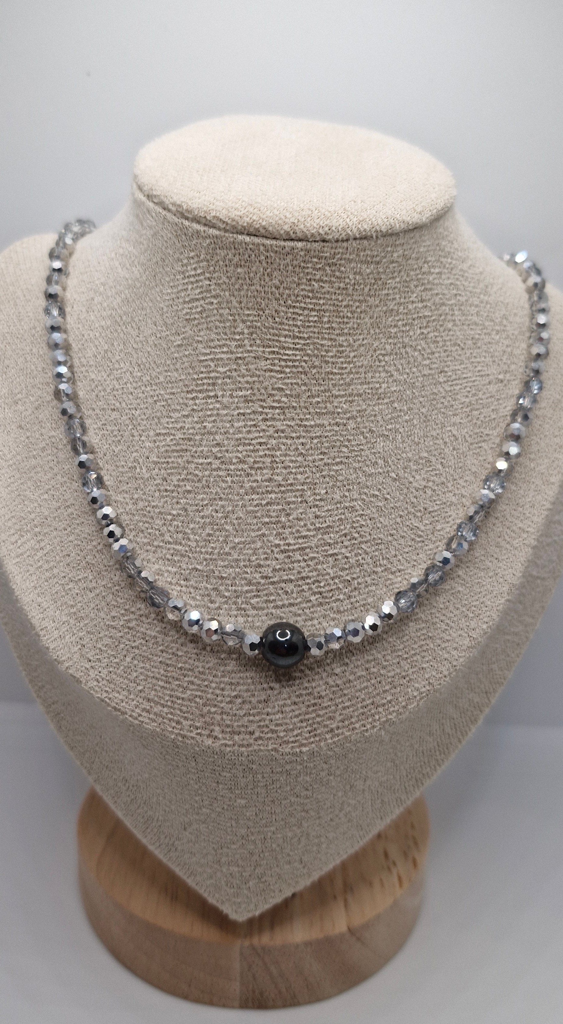 Silver bracelet with a black stone on a beige jewelry display.