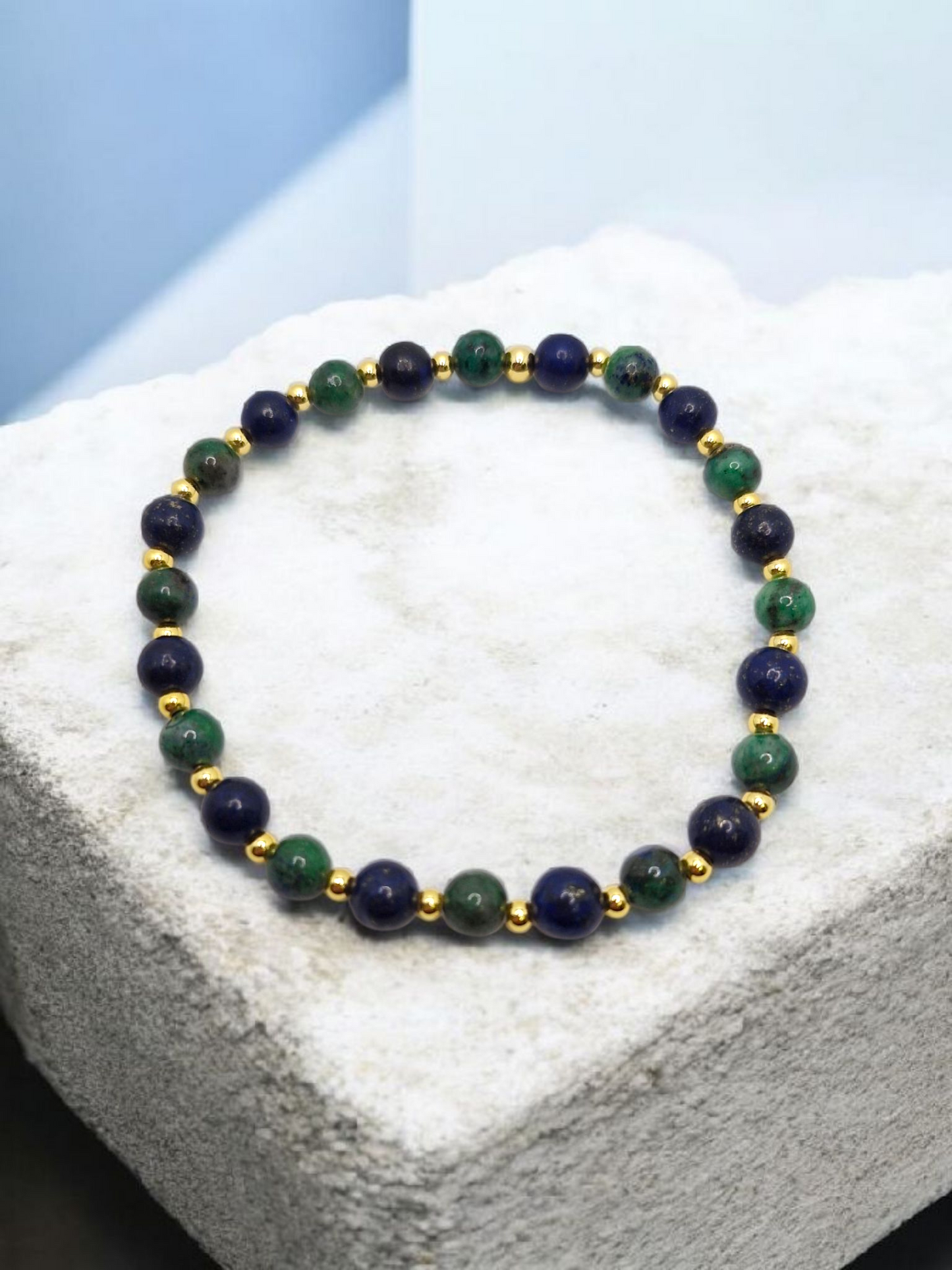 Bracelet with green and gold beads on a white surface