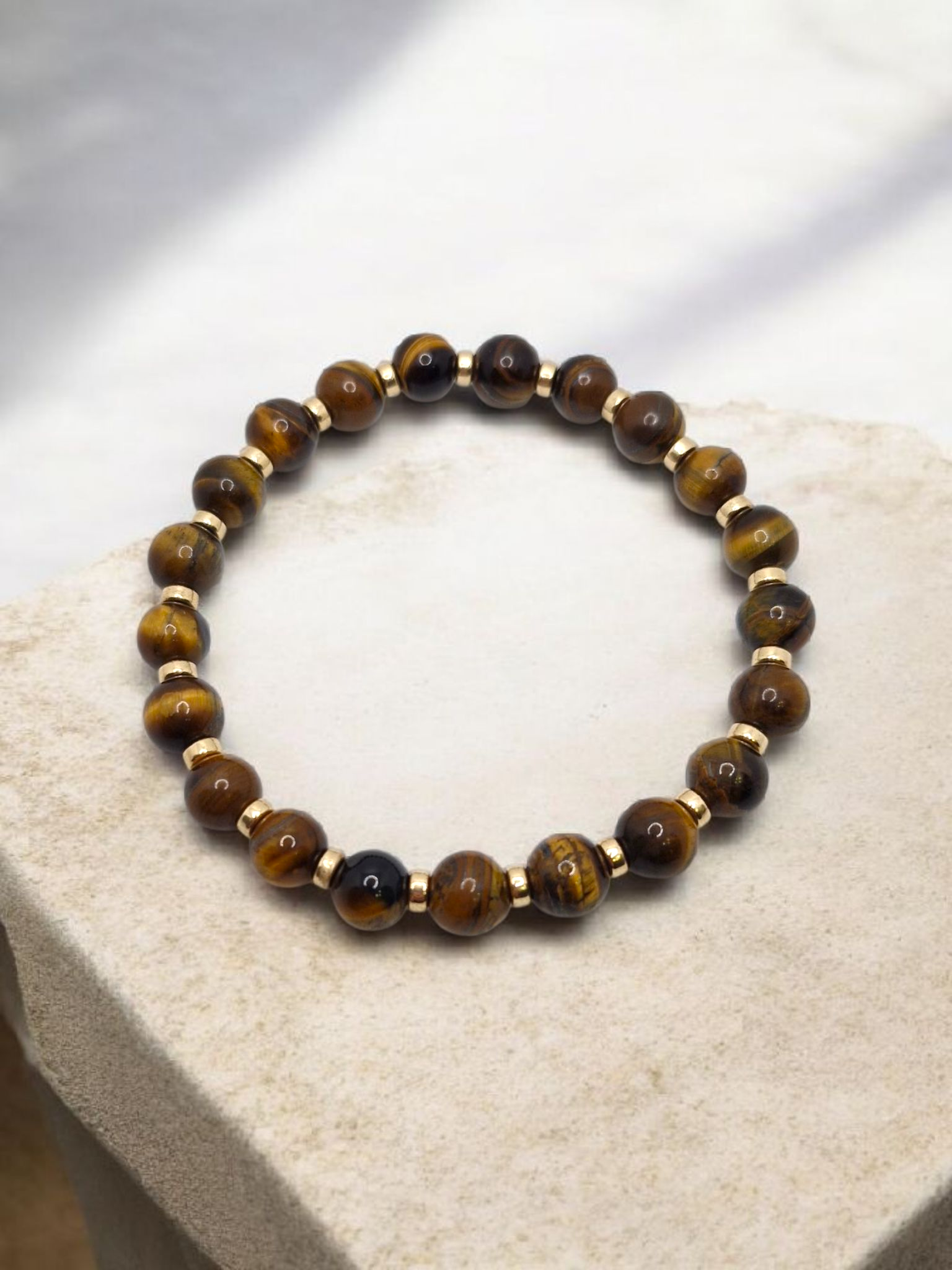 Beaded bracelet with brown and gold beads on a textured surface